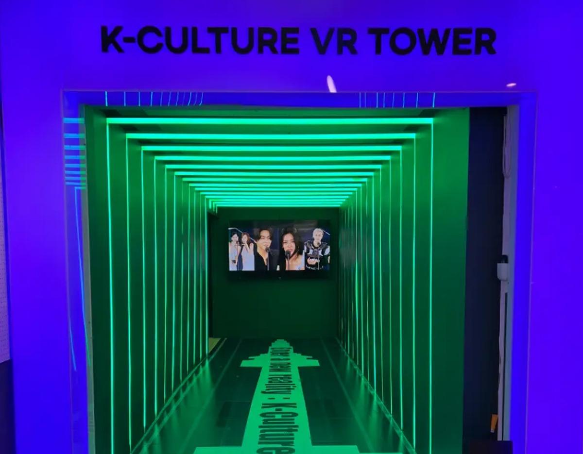 K-Culture VR Tower entrance tunnel with purple frame, green LED lighted rectangular ribs and a screen showing K-pop performers.
