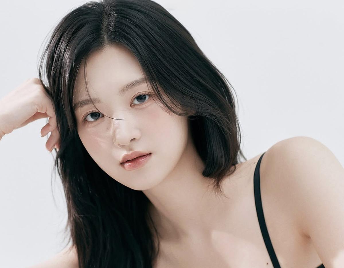 young woman with long dark hair in a black top posing in a clean studio portrait