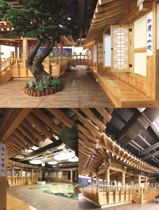 Traditional wooden interior with curved pine tree, raised wooden walkways, lattice windows and Korean hanok-style details.