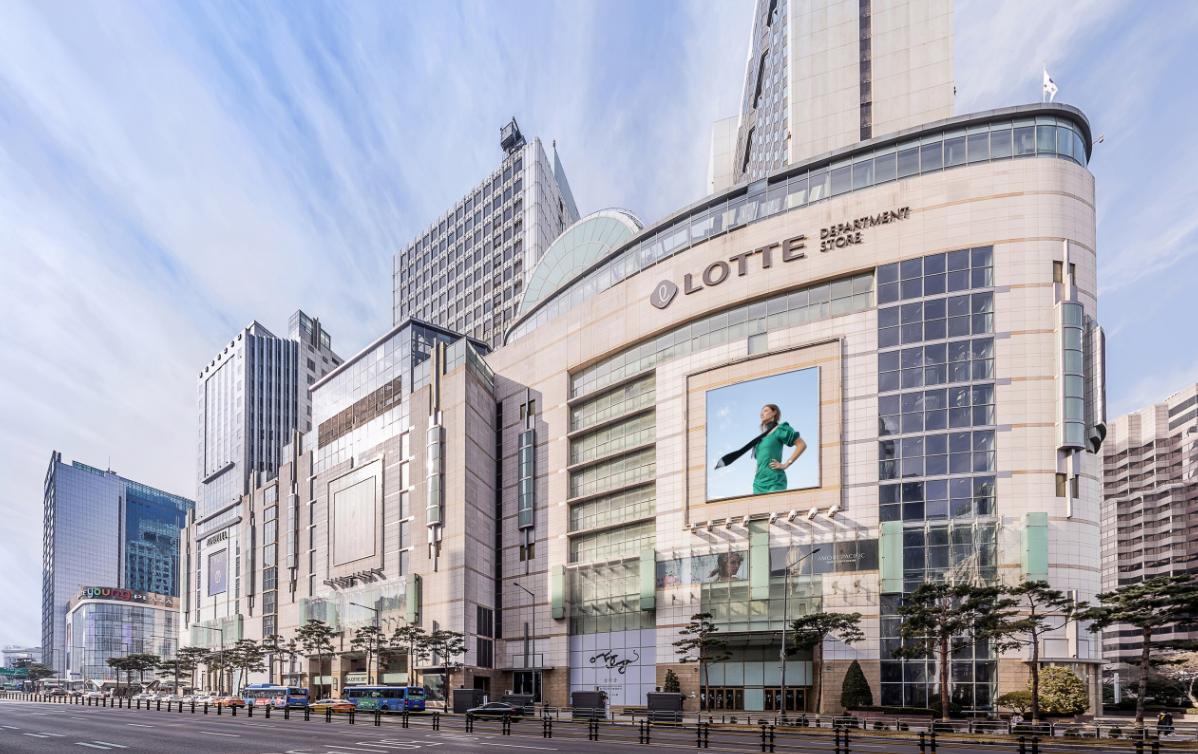 Lotte Department Store facade in Jung-gu, Seoul with large LED billboard and multi-story glass and stone mall exterior under pale sky