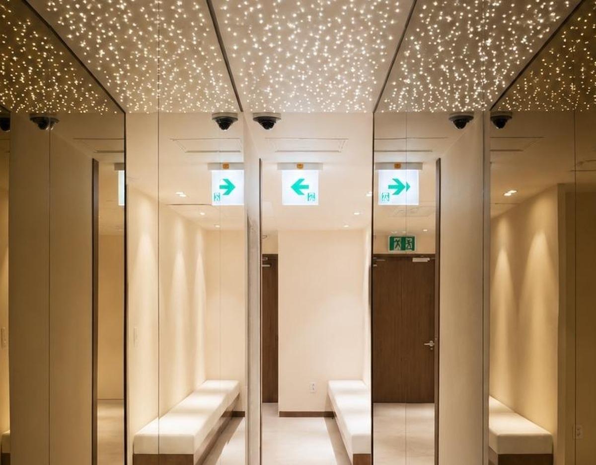 고트의원 waiting area with mirrored walls, cushioned white benches and starry ceiling lights reflected in mirrors