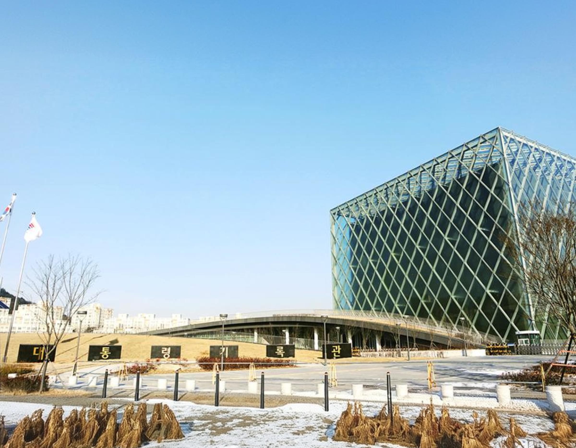 Sejong presidential archives building with glass lattice facade, curved rooftop garden and snowy foreground at clear sky