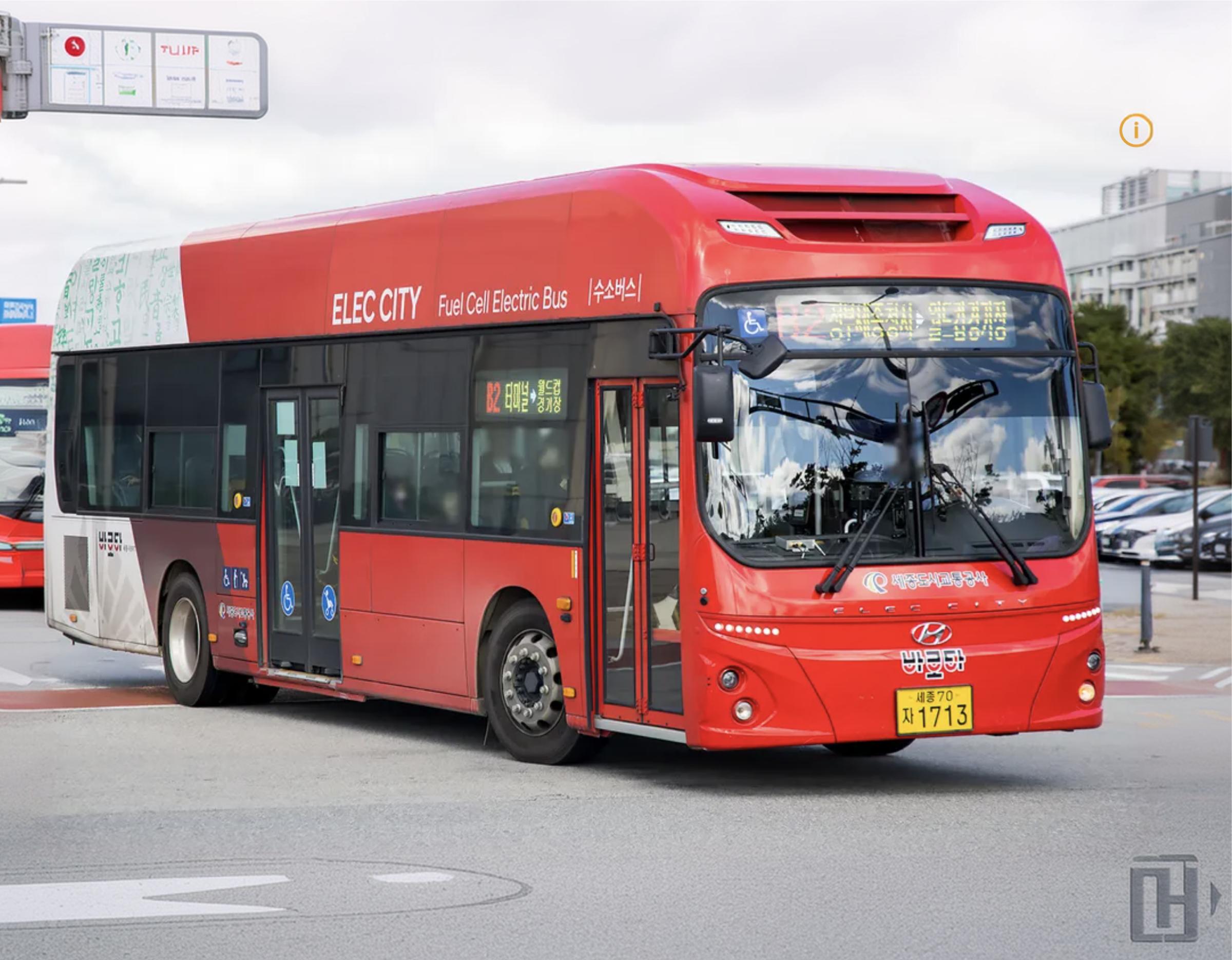 Red fuel-cell electric city bus with "ELEC CITY" lettering at a Sejong BRT stop, showing side doors and front windshield.