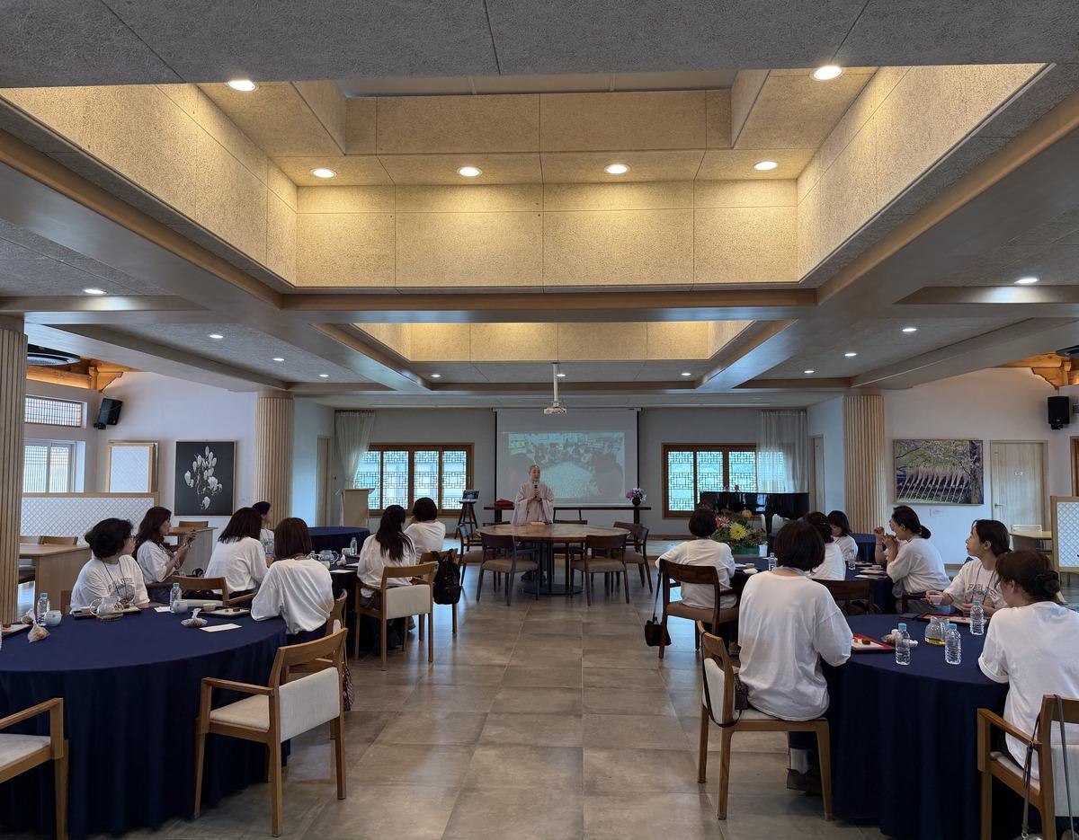 소울트레일 in 금정산 웰니스 프로그램 참가자들이 넓은 실내 강당에서 둥근 테이블에 앉아 강사 프레젠테이션을 듣는 모습