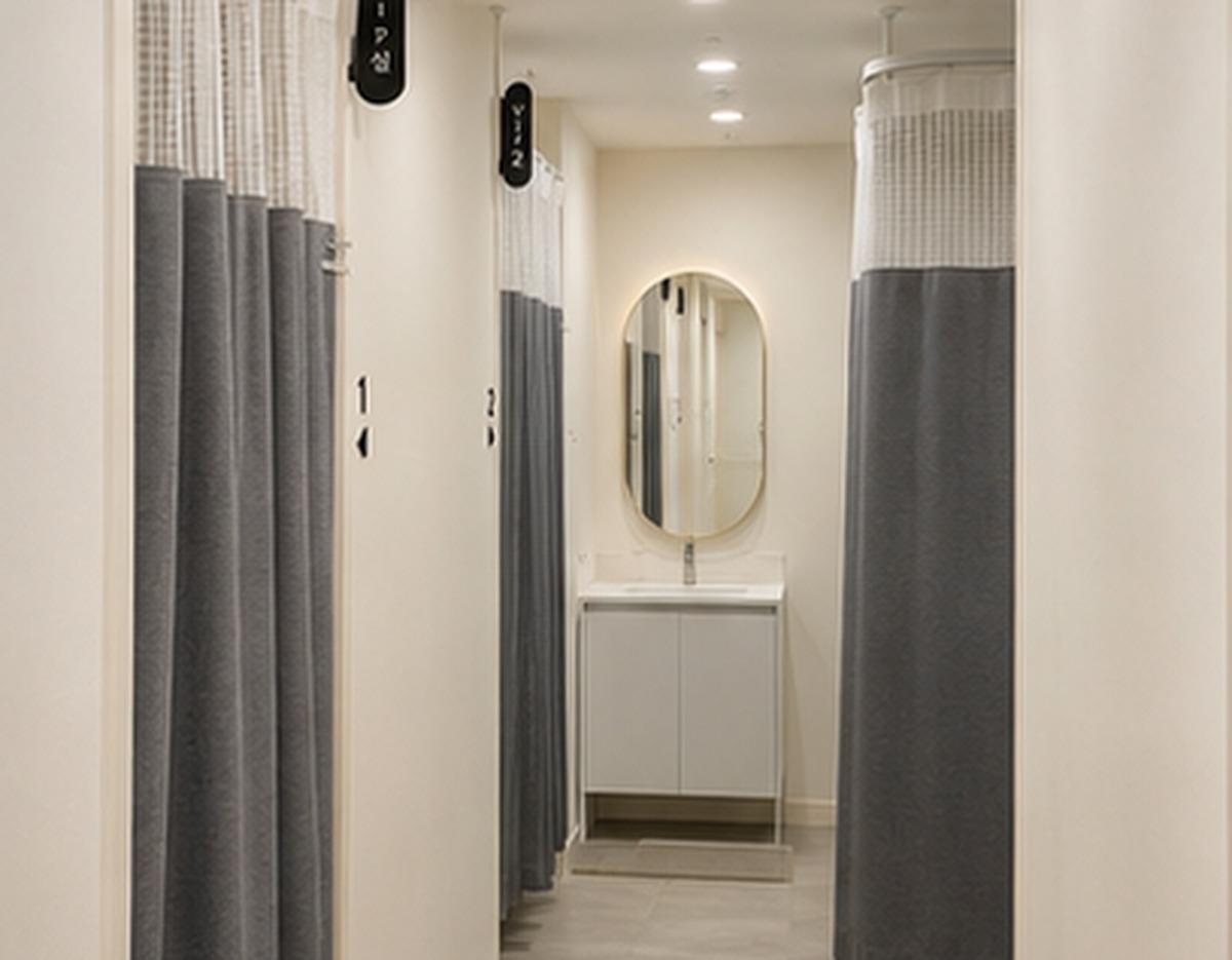 Bon Jung Korean Medicine Clinic narrow treatment corridor with numbered gray privacy curtains and a sink with oval mirror.