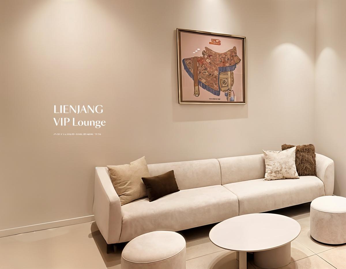Minimalist VIP lounge with beige sofa, round coffee tables, plush cushions and framed artwork on cream wall at Lienjang Myeongdong.