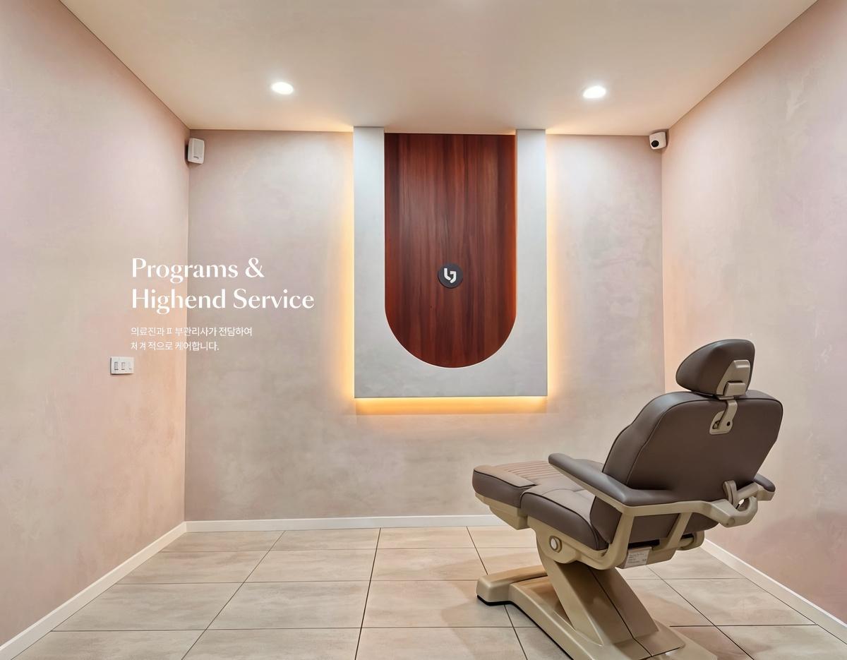Minimal private treatment room with beige reclining medical chair, soft pink walls and backlit wood-accent wall panel