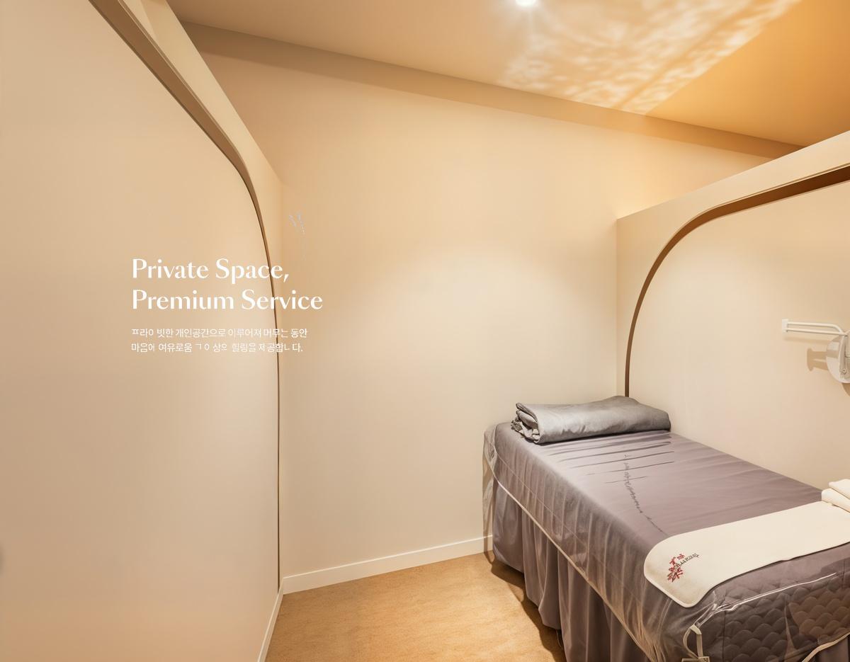 Private treatment room with single massage bed, gray linens, folded towels and warm cream-colored minimalist decor.