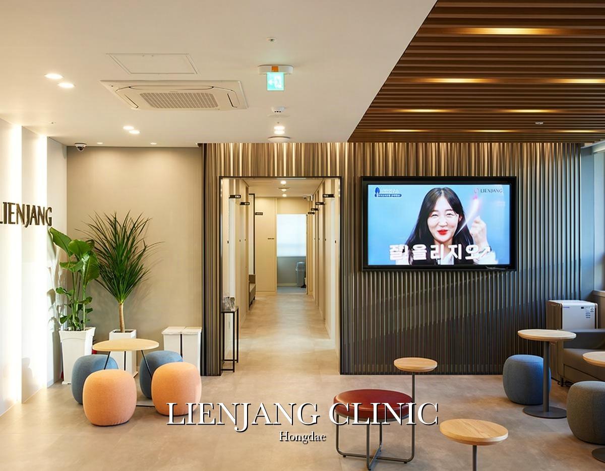 Modern clinic waiting area with round stools, small tables, potted plants and a wall TV at Lienjang Clinic Hongdae.