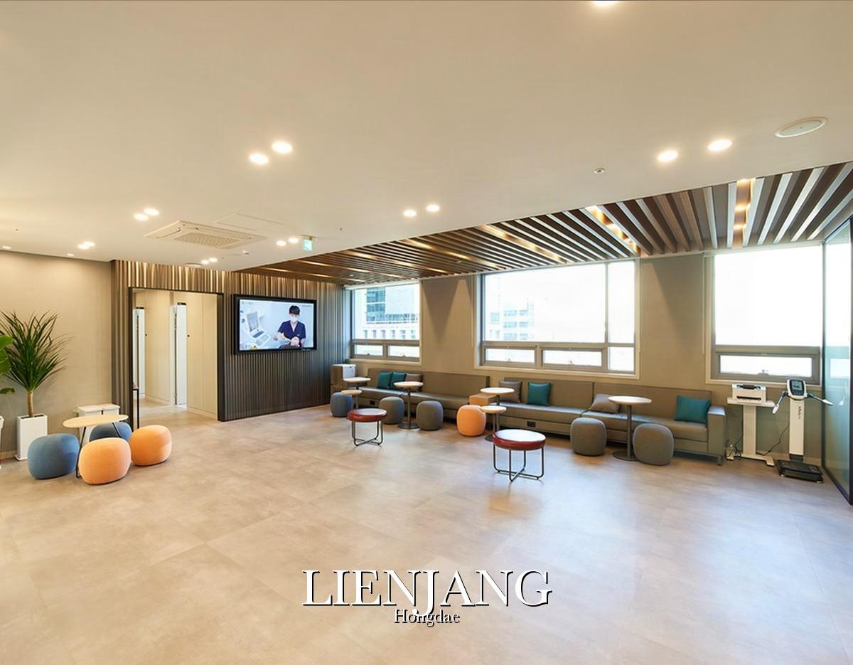 Bright modern clinic waiting area with low sofas, round ottomans, small tables, TV and large windows, Lienjang Hongdae.