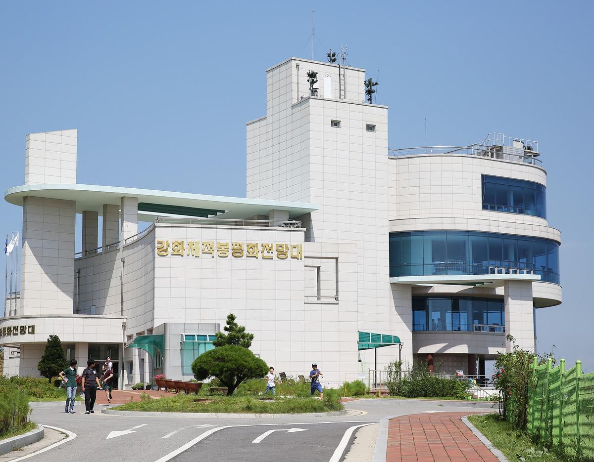 Ganghwa Peace Observatory building with cream tiled facade, curved glass viewing decks and visitors on pathway