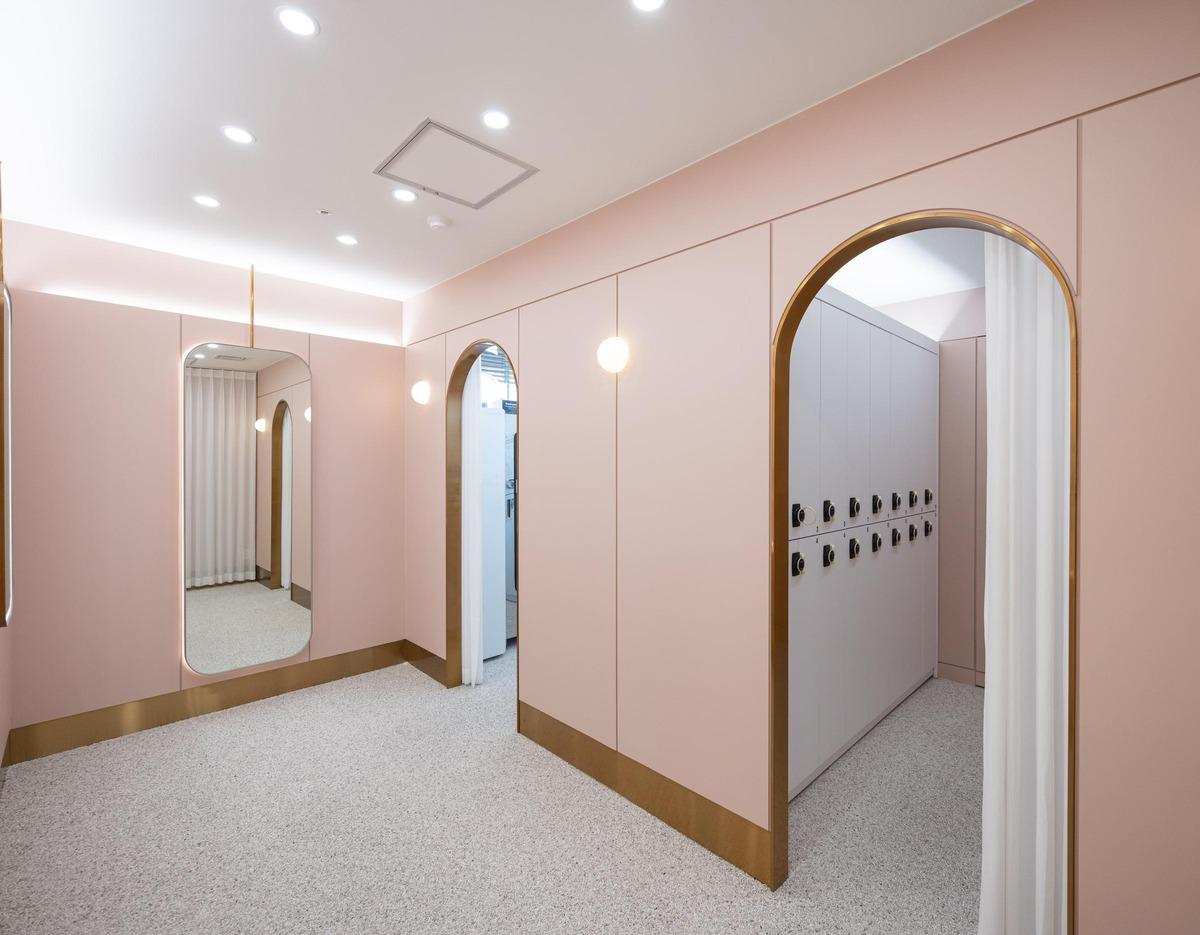 365mc병원 부산점 pink-toned locker room with arched doorways, wall mirror, round lights and row of white lockers