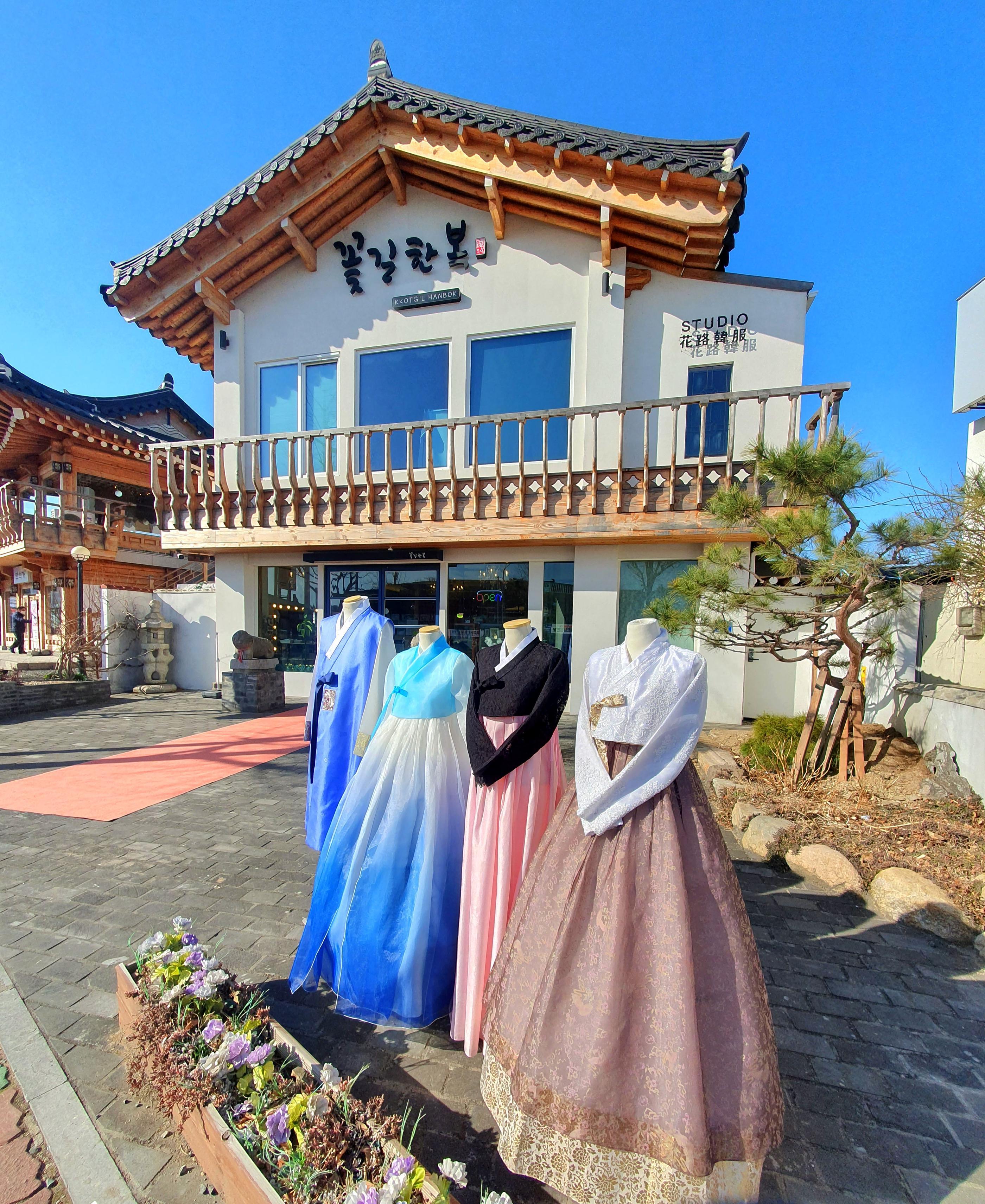 Hanbok rental studio exterior on Hwangridan-gil with four colorful hanbok dresses on mannequins under a traditional tiled roof