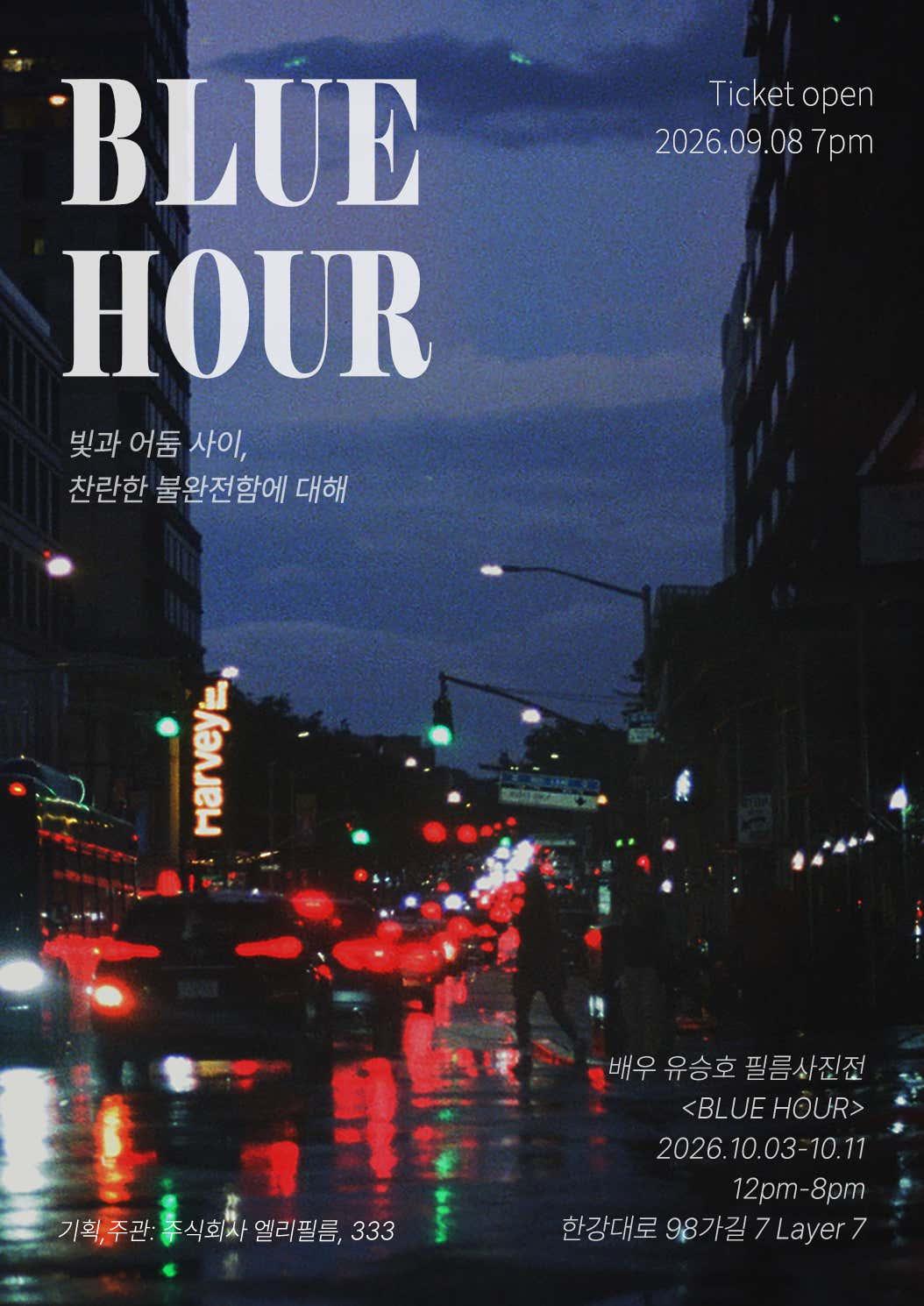 rainy city street at dusk with blurred car taillights reflecting red on wet pavement and large "BLUE HOUR" text overlay