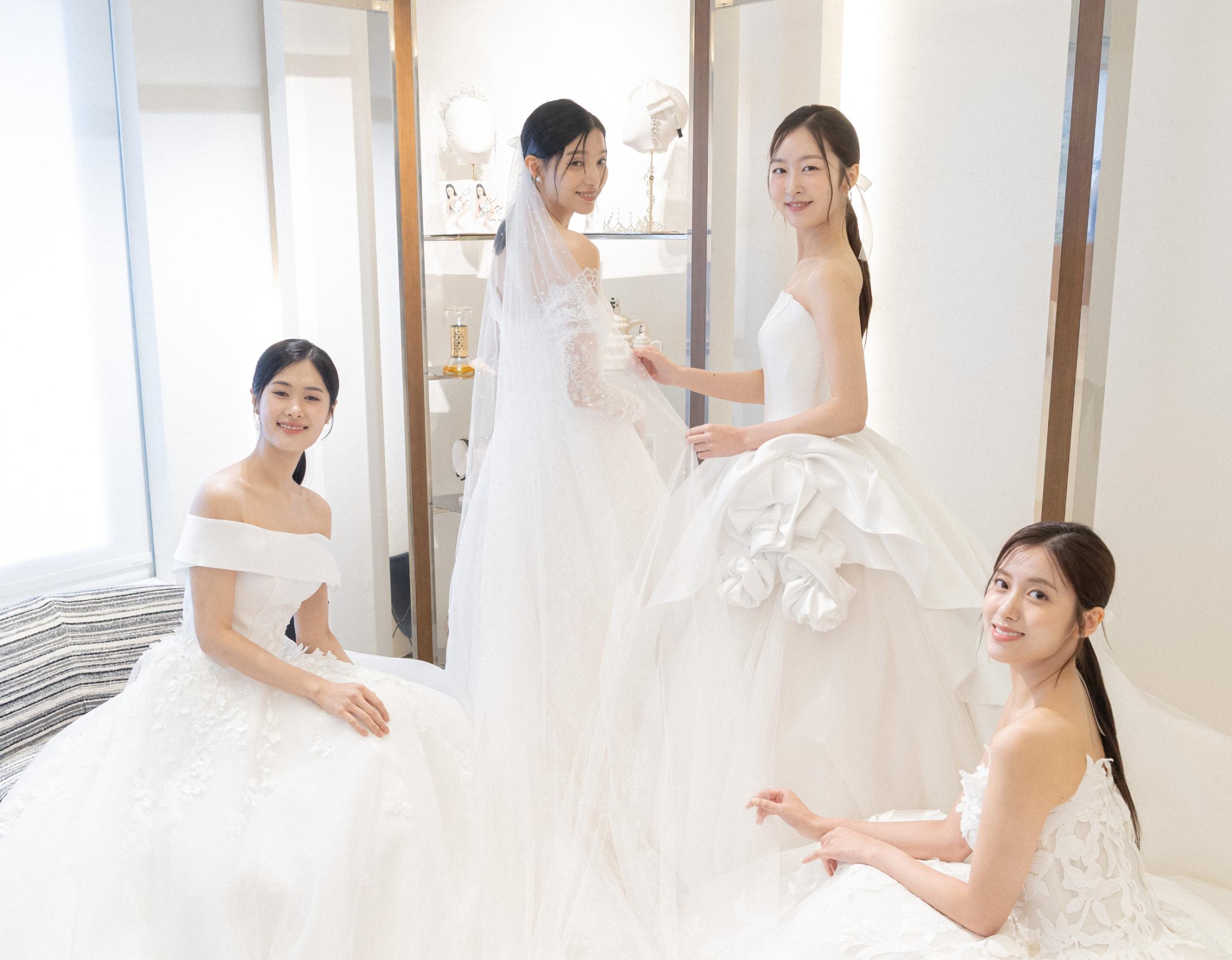 까라디 salon bridal scene with four women in different white wedding gowns posing in a bright fitting room