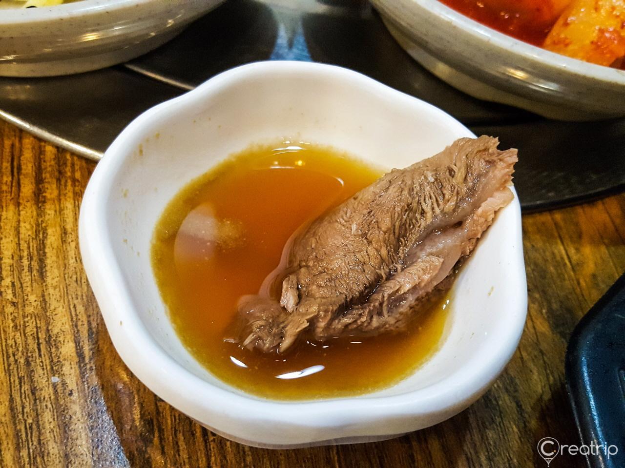 A plate of traditional Korean food at 함평면옥, featuring 갈비탕 (beef short rib soup), fried fish, and produce.