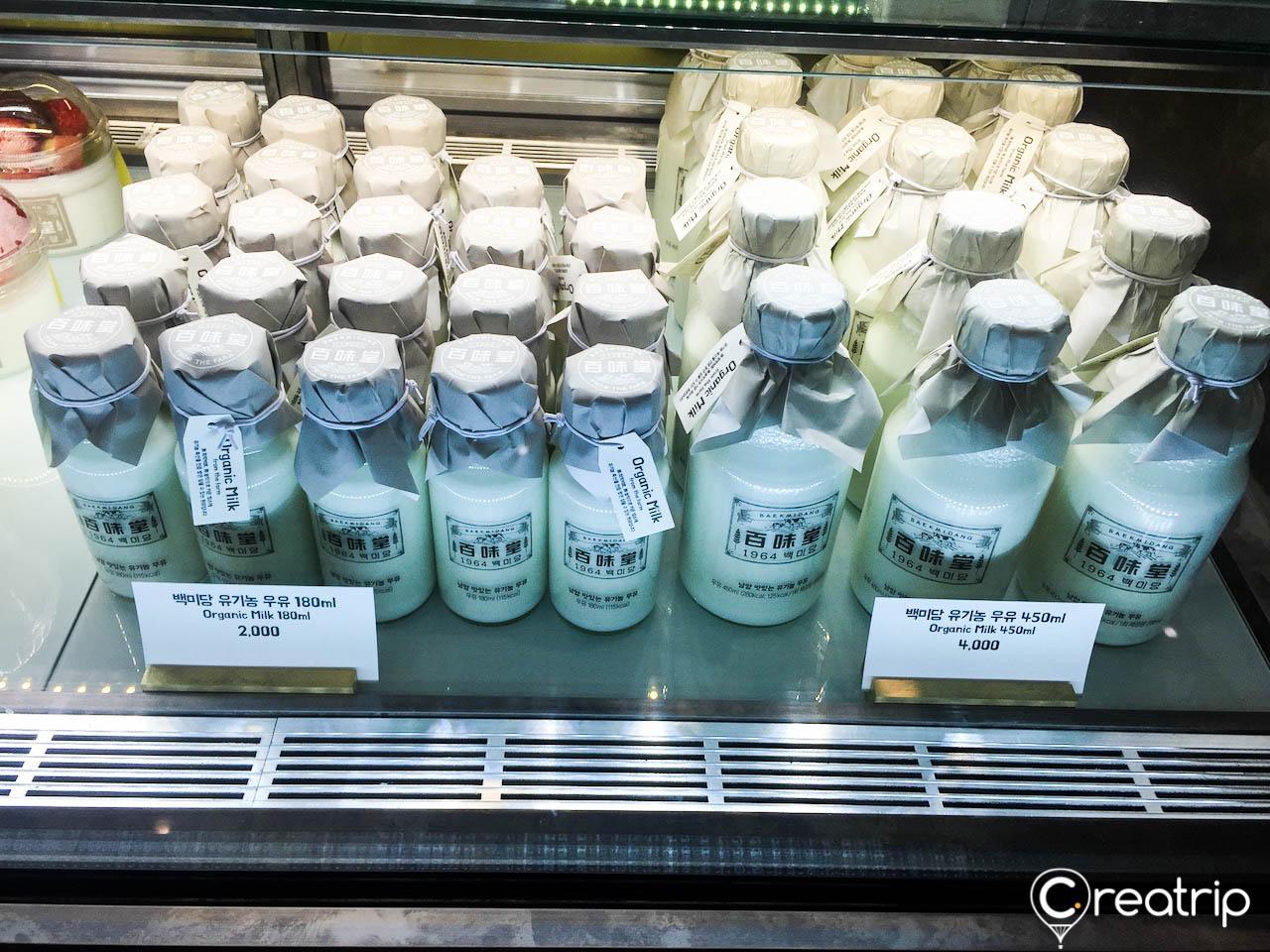 A variety of drinks displayed on shelves in a store, including milk beverages, bottled solutions, and gas drinks. Location: Seoul, Korea.