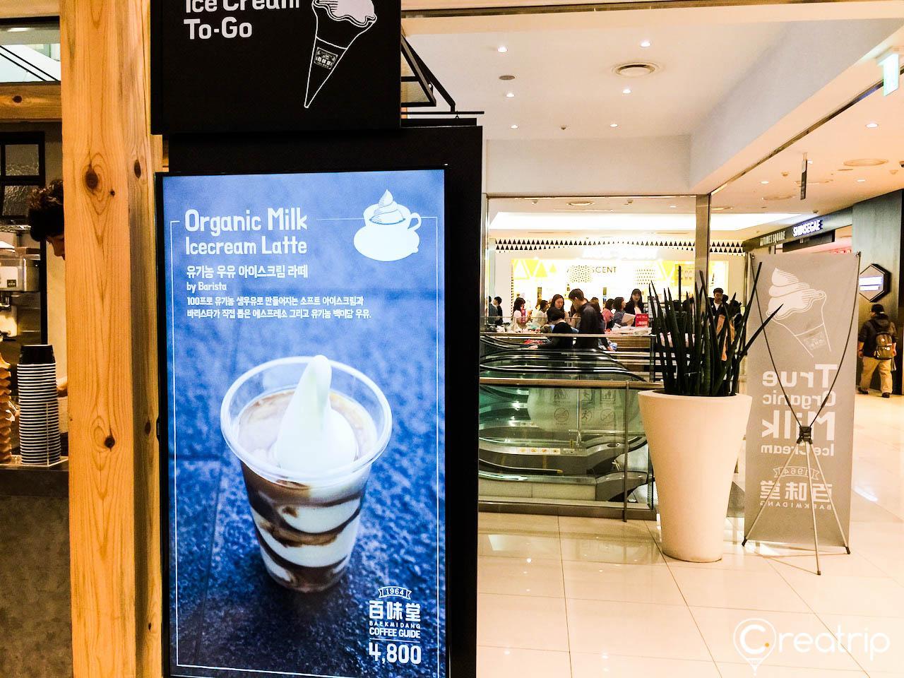 A coffeehouse display featuring plants and flowerpots in a building with flooring and advertising.