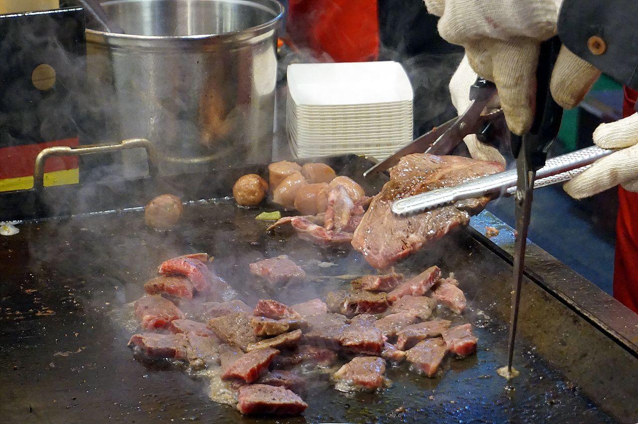 Roasting beef at the bustling street food market in Busan, Korea.