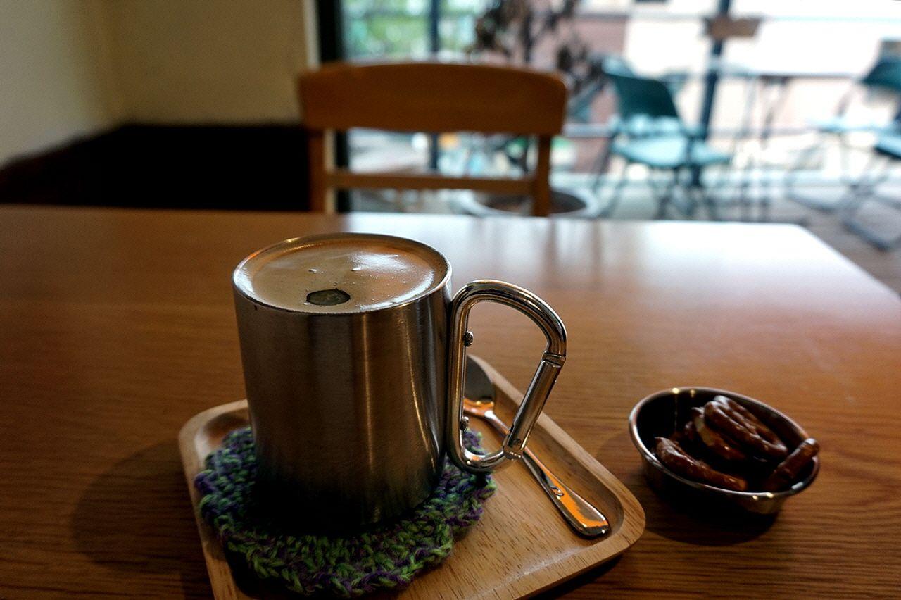 A wooden table with cups and drinkware at a Korean cafe.