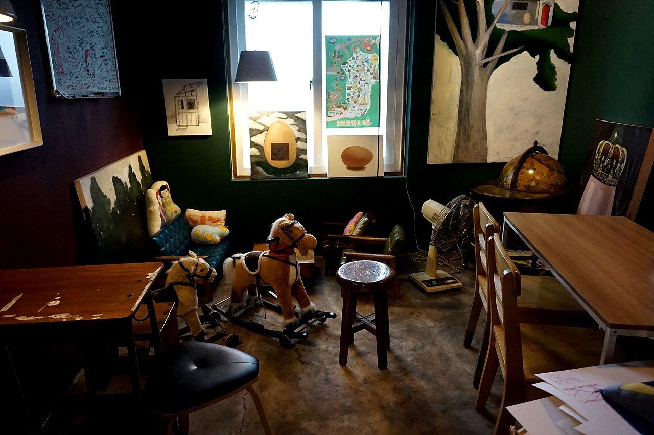 Interior of Korean cafe showcasing wooden furniture, property decor, picture frames, and wall art.