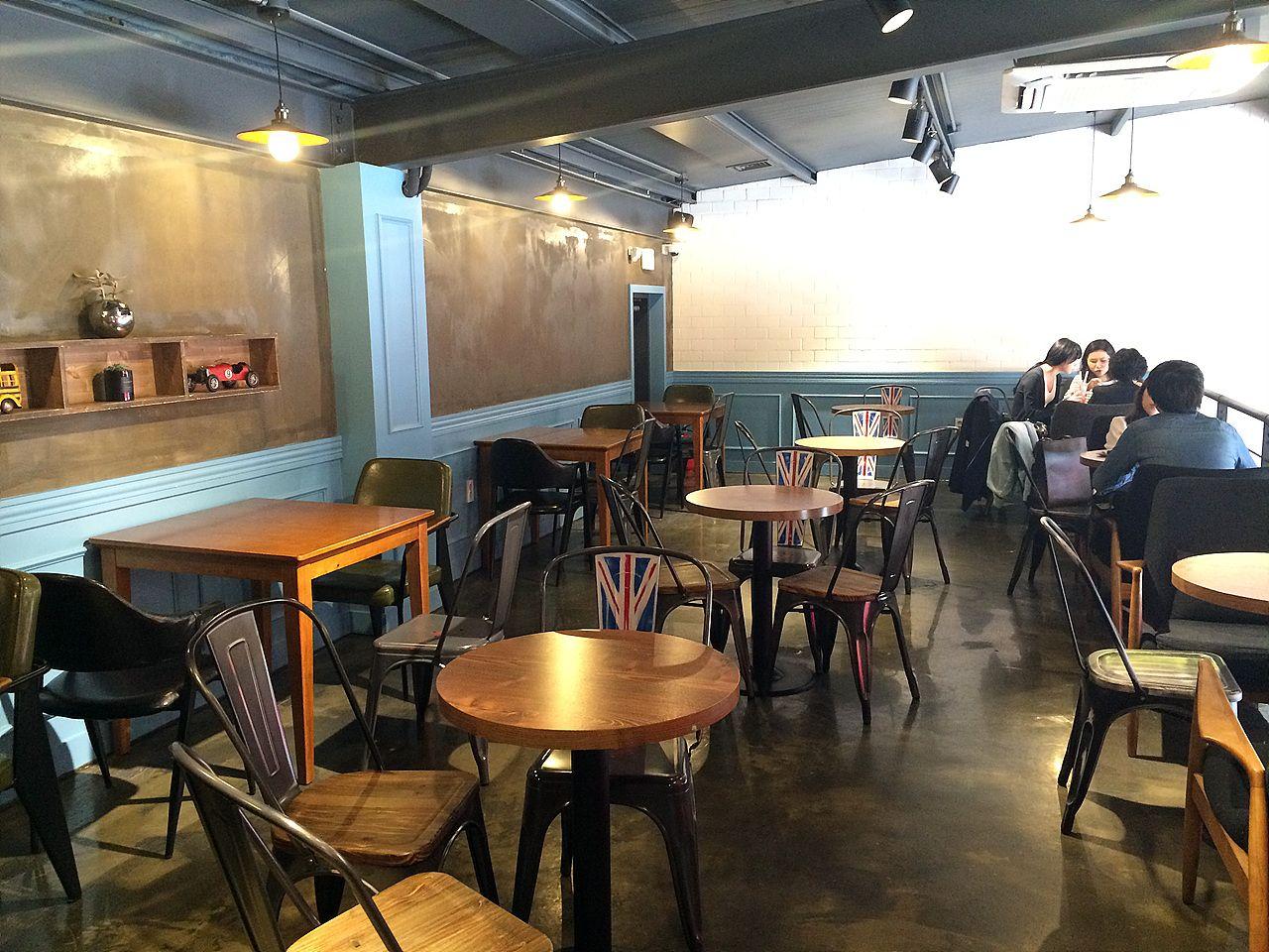 Interior of a modern café in Seoul with stylish furniture, including chairs, tables, and lighting. The flooring and organization of the space are well-designed.