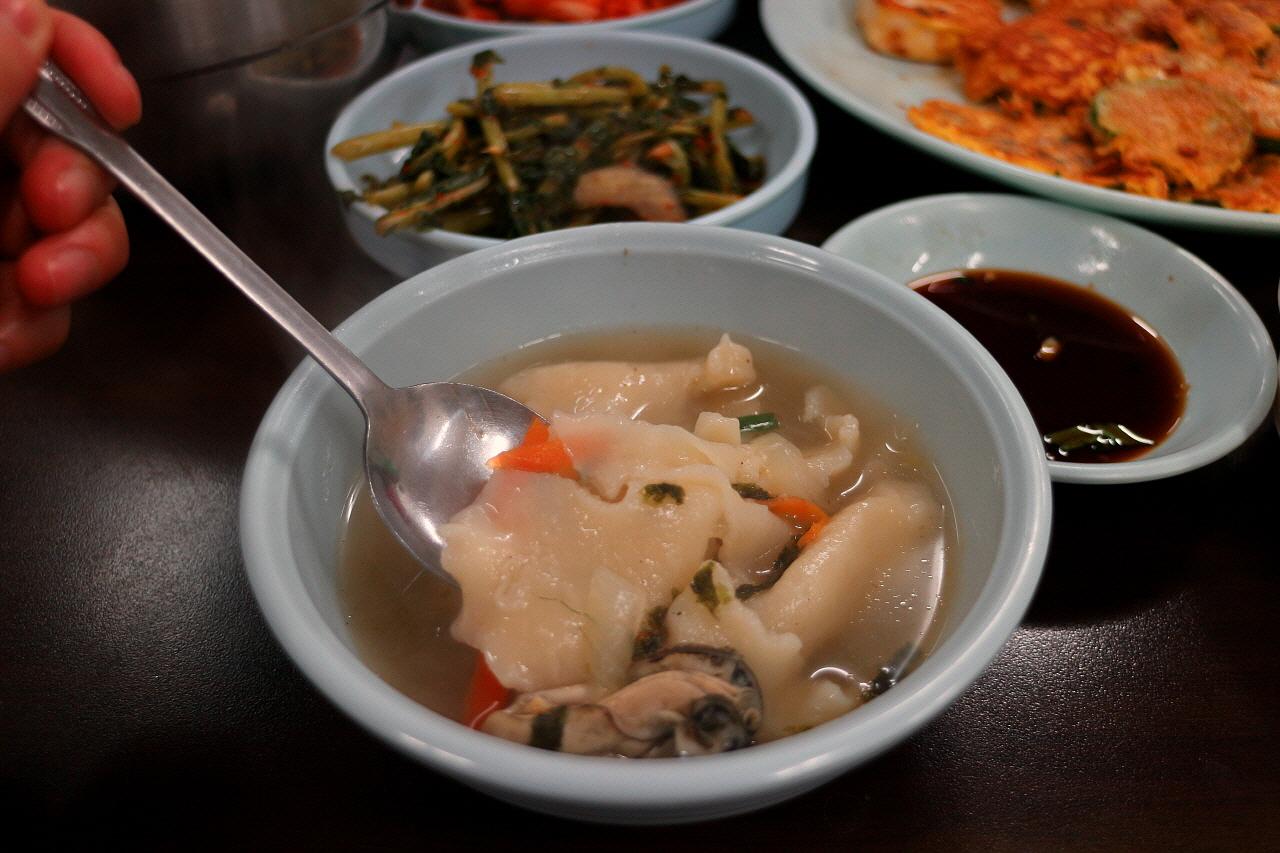 Traditional Korean dish 수제비 (handmade noodles) served in tableware with ingredients and kitchen utensils.