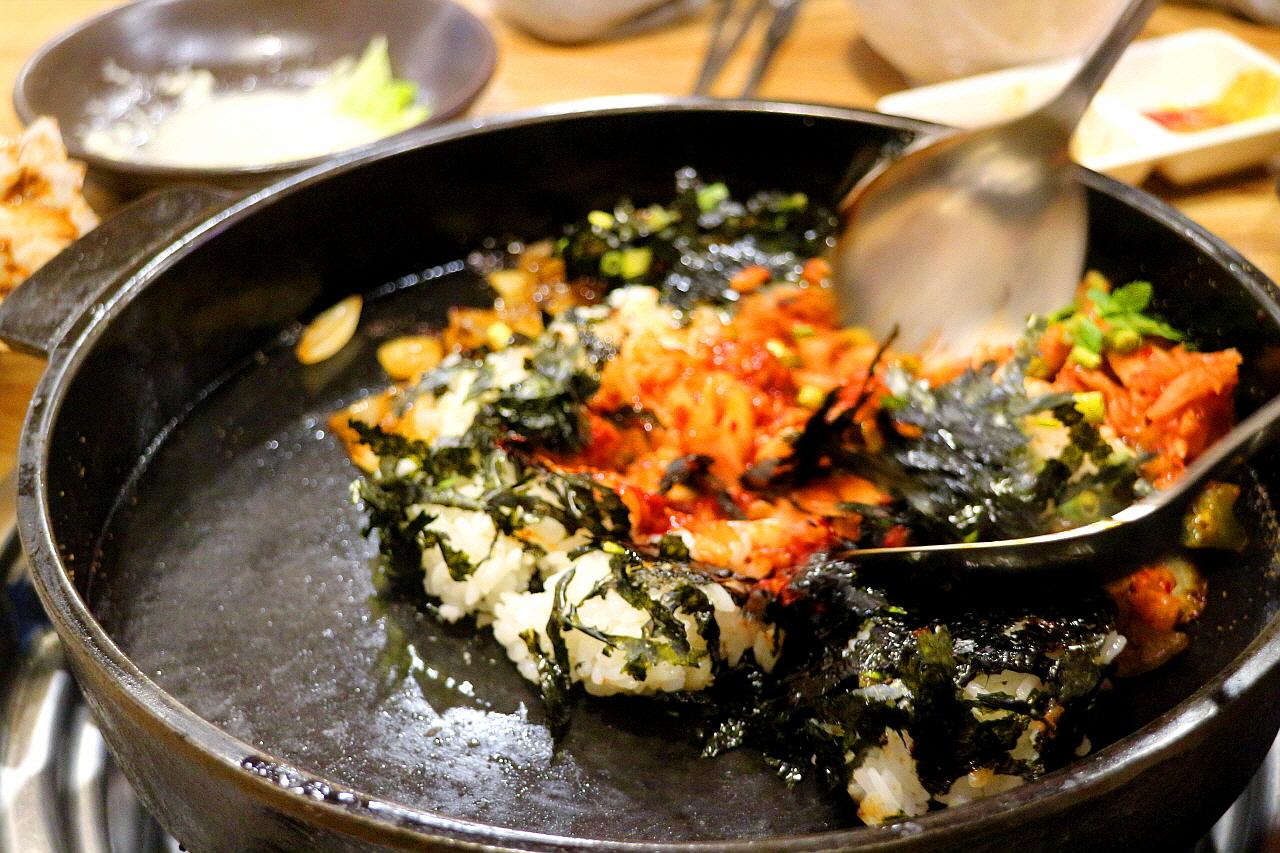 Comfort food dish of furry beef steak with leafy greens and cooking utensils for recipe in Korean cuisine.