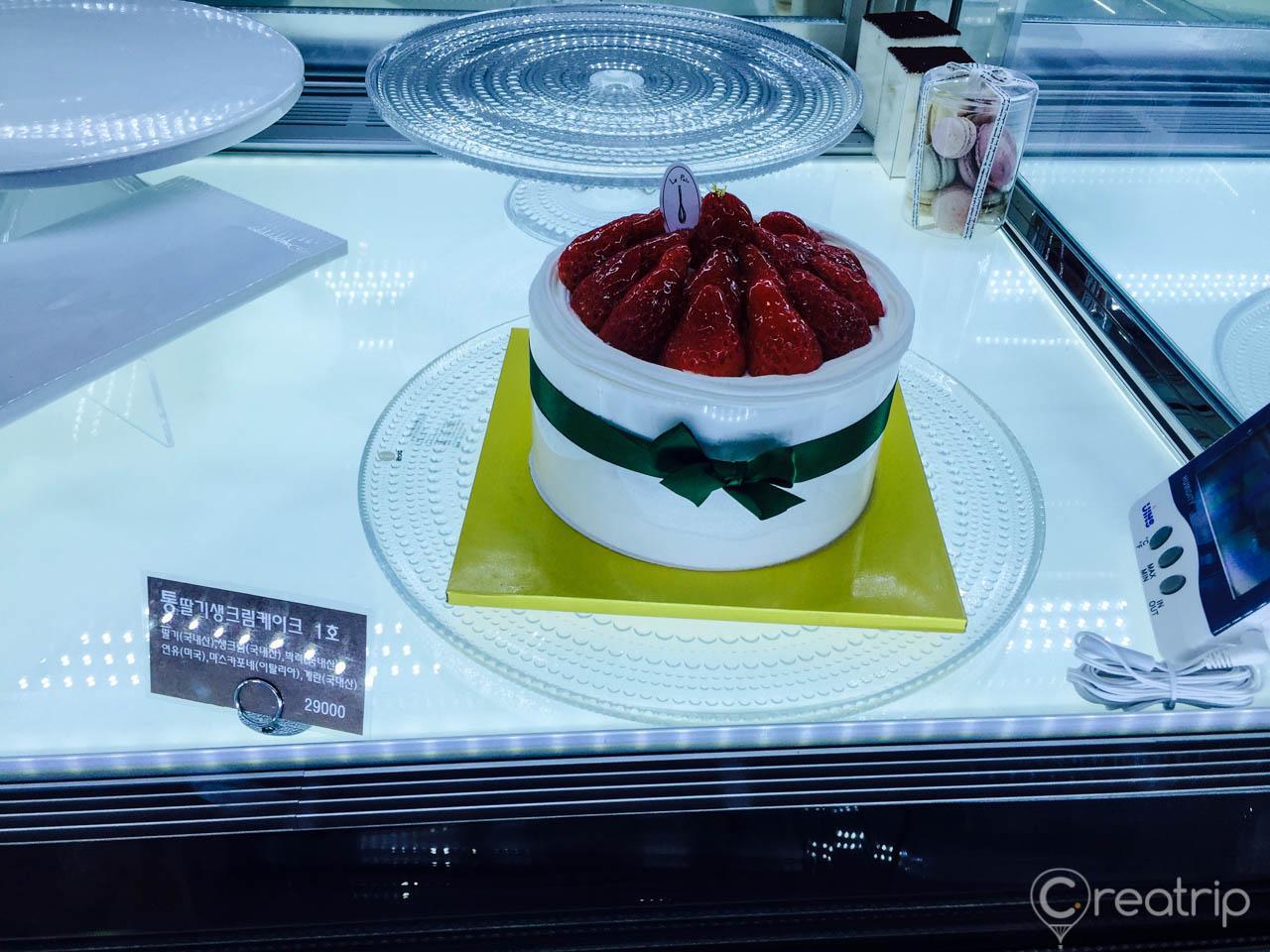 bakery display featuring various cakes, ingredients, and tableware, inside the 1898 Plus souvenir shop at Myeongdong Cathedral in Korea.