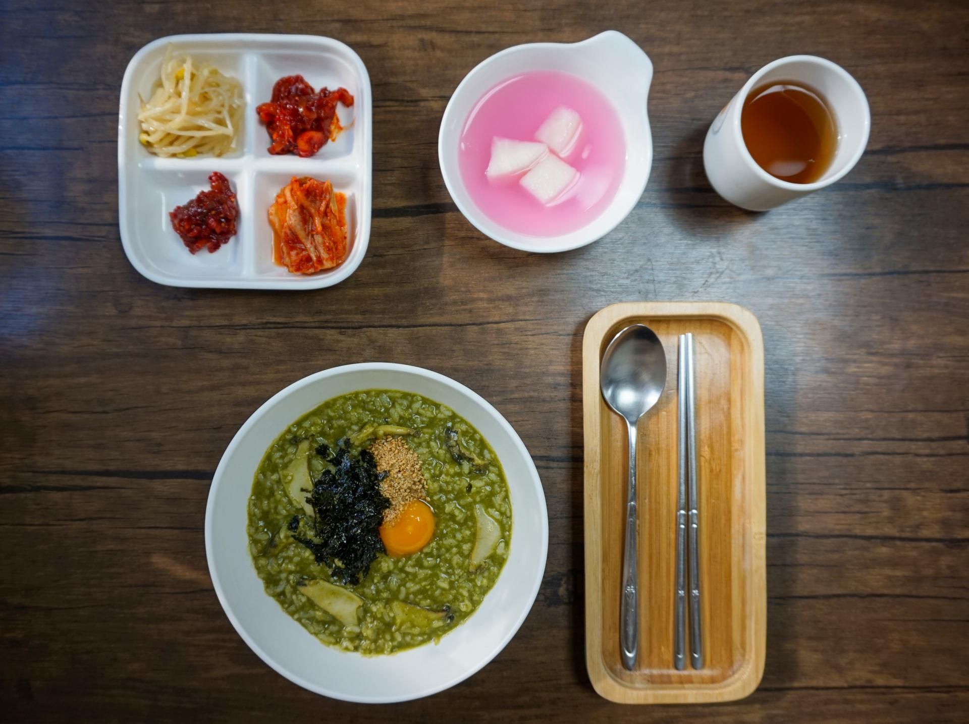 Tableware with dishes and ingredients including broccoli, served in a Korean cuisine restaurant.