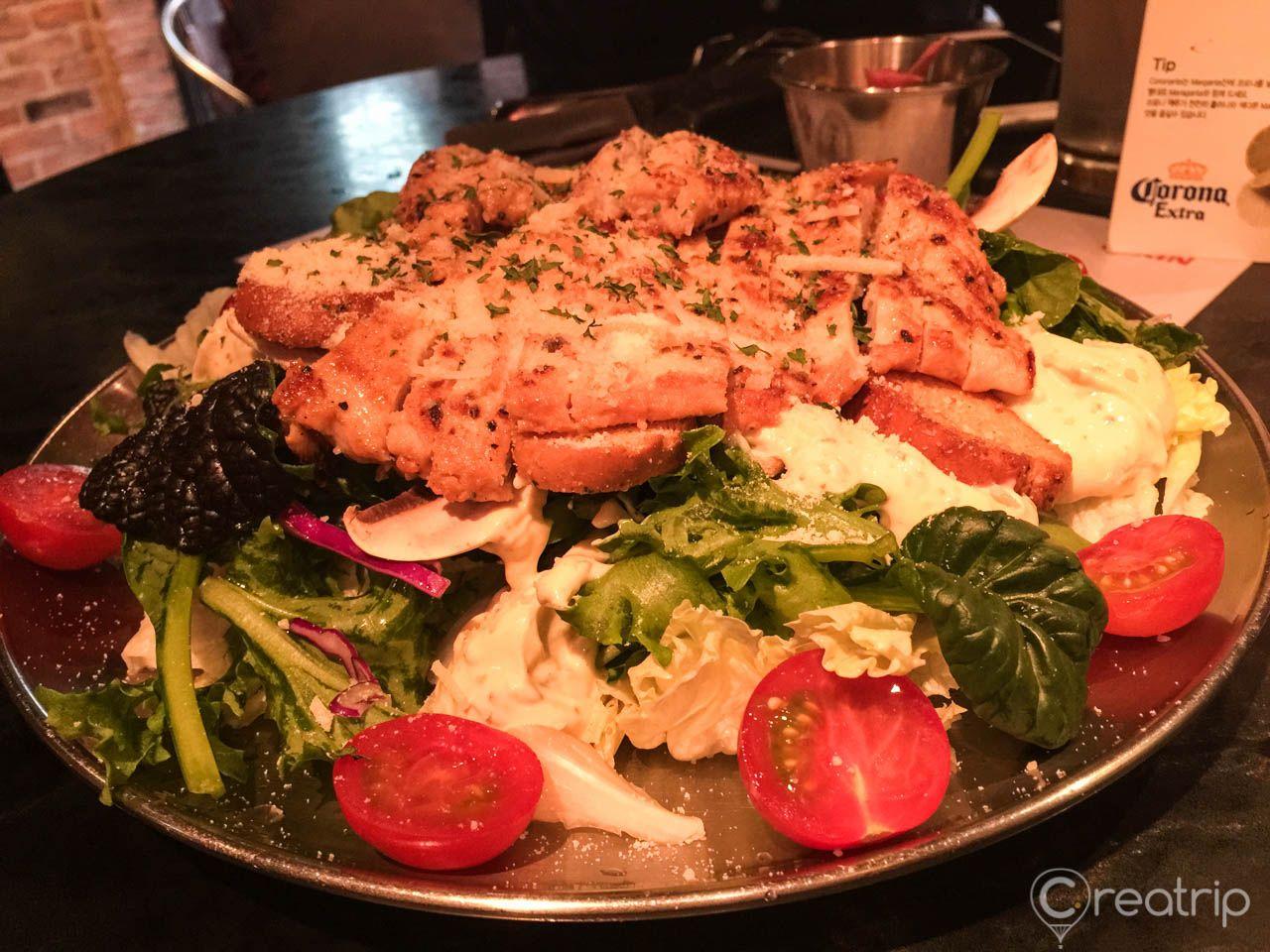Plate of Jacoby Burger surrounded by tableware, ingredients, and leaf vegetables for Christmas dinner.