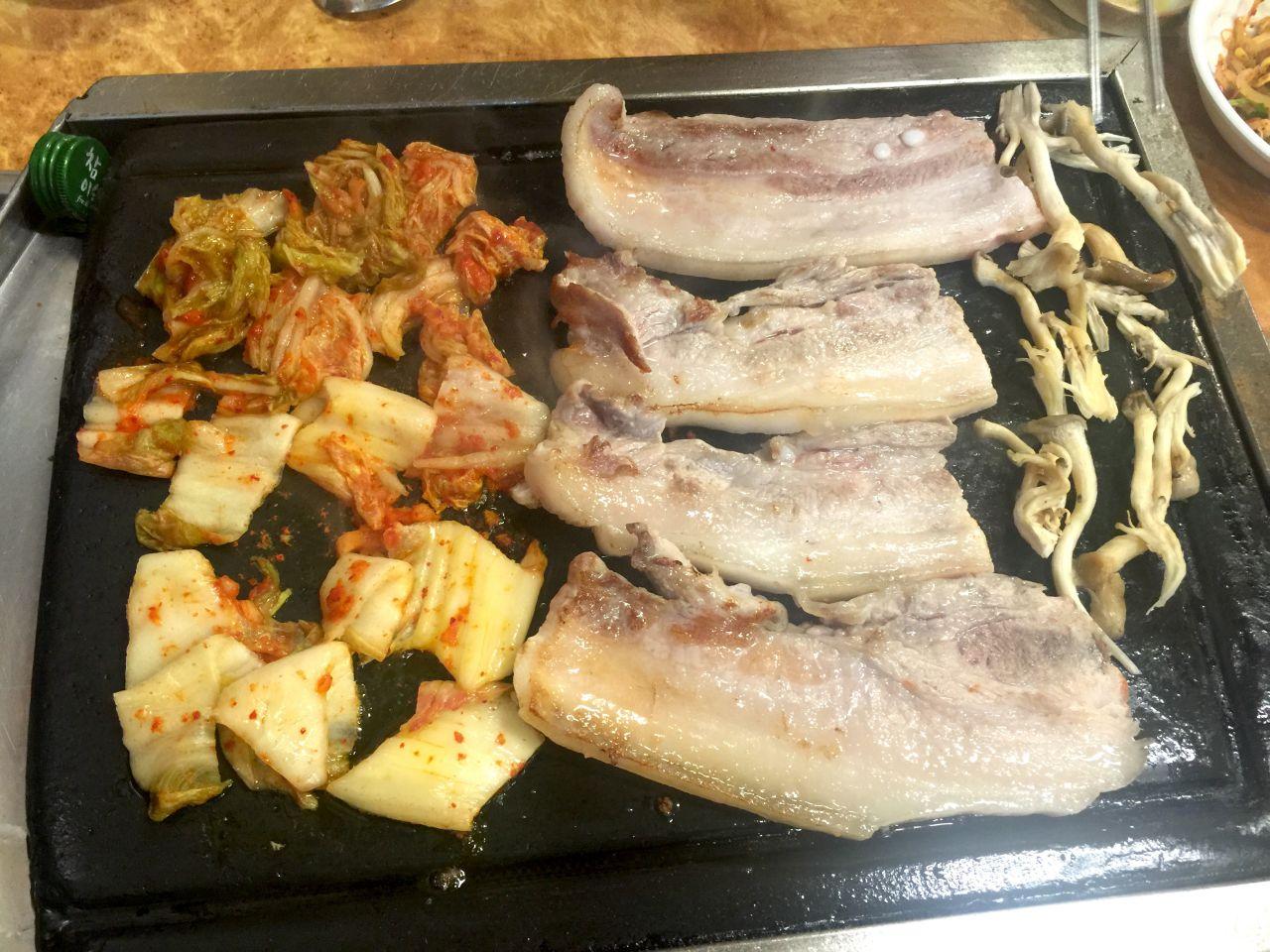 Delicious pork belly (삼겹살) dish served on a table with various ingredients and seafood in Korea.