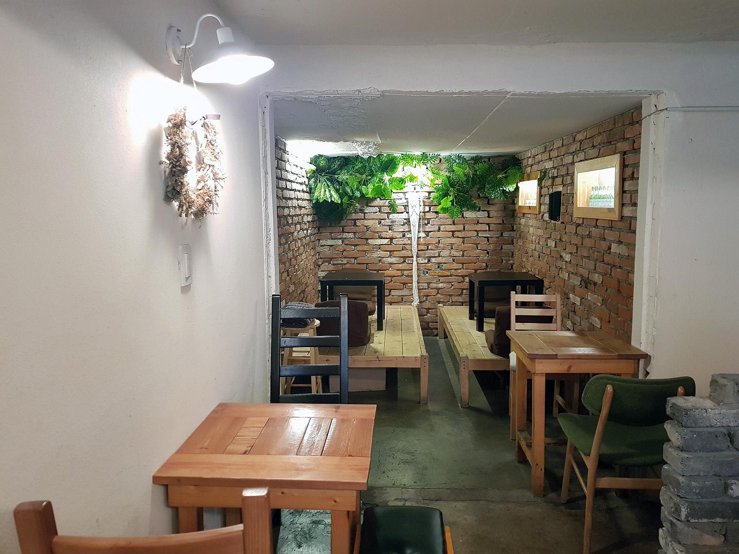 Interior of <Annyeong, Natsun Sarang> restaurant in Seoul with wooden furniture, houseplants and flooring.