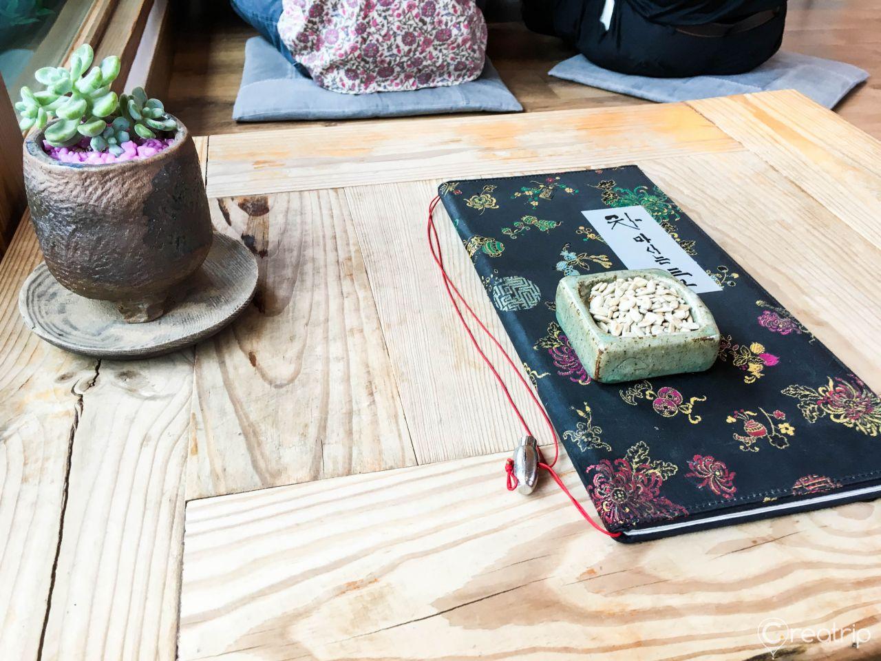Table setup in a Korean courtyard with purple tableware, wooden table, and textile accents.