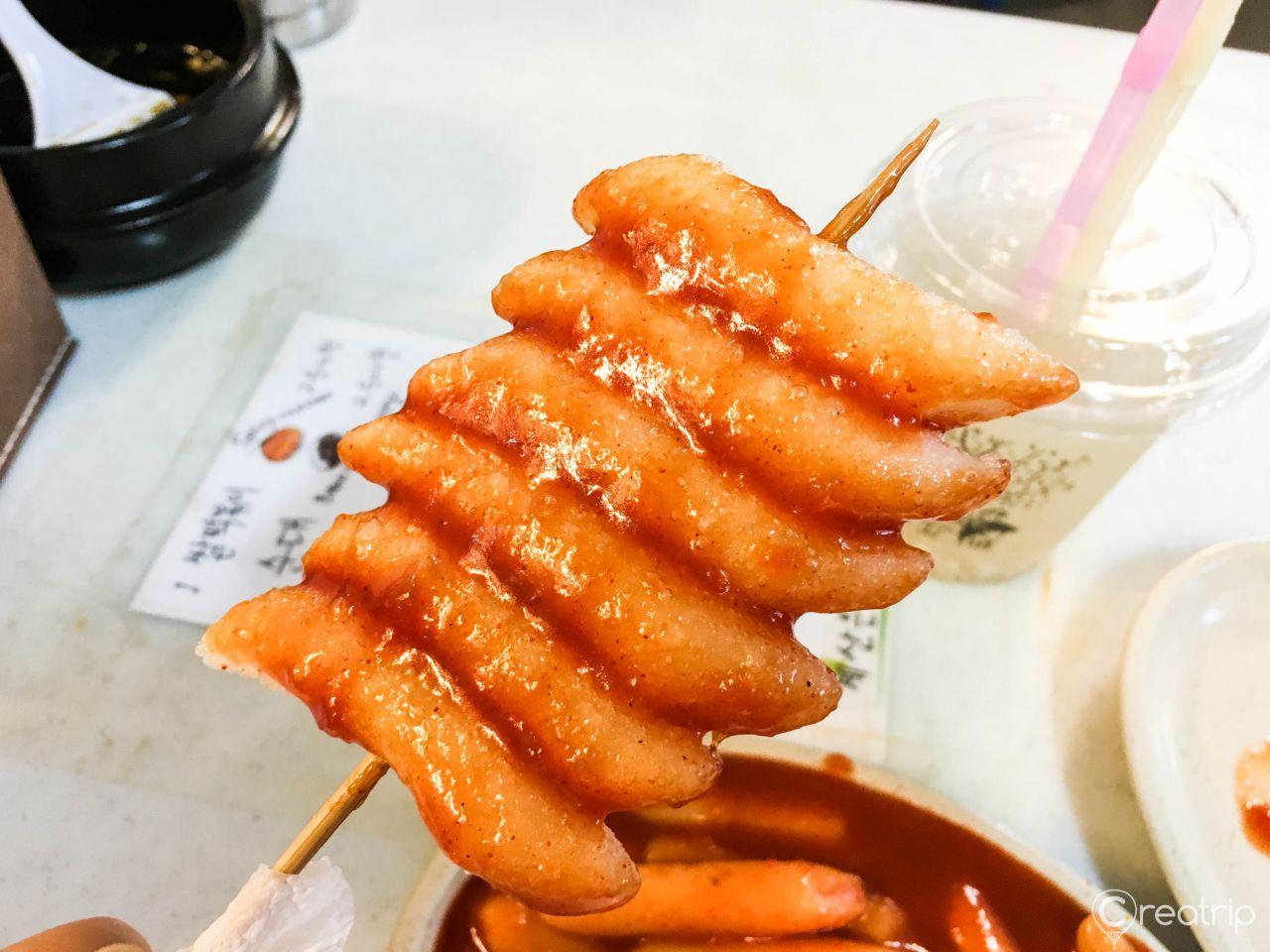 A dish of spicy Korean street food, 떡볶이 (tteokbokki), made with fresh seafood and served with rice.