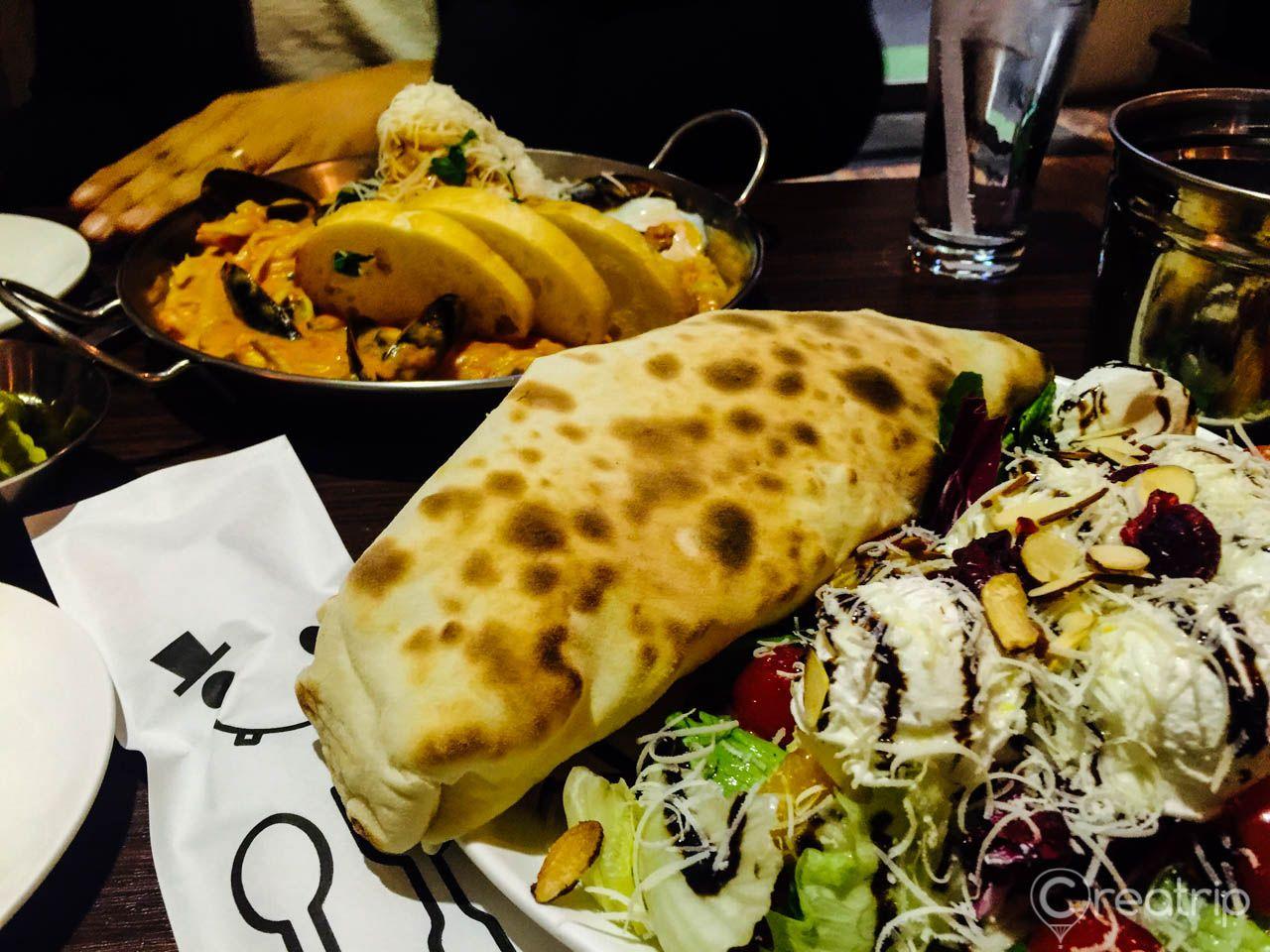 Colorful spread of dishes from Pasta Market including burritos, baked goods, and tableware on display.