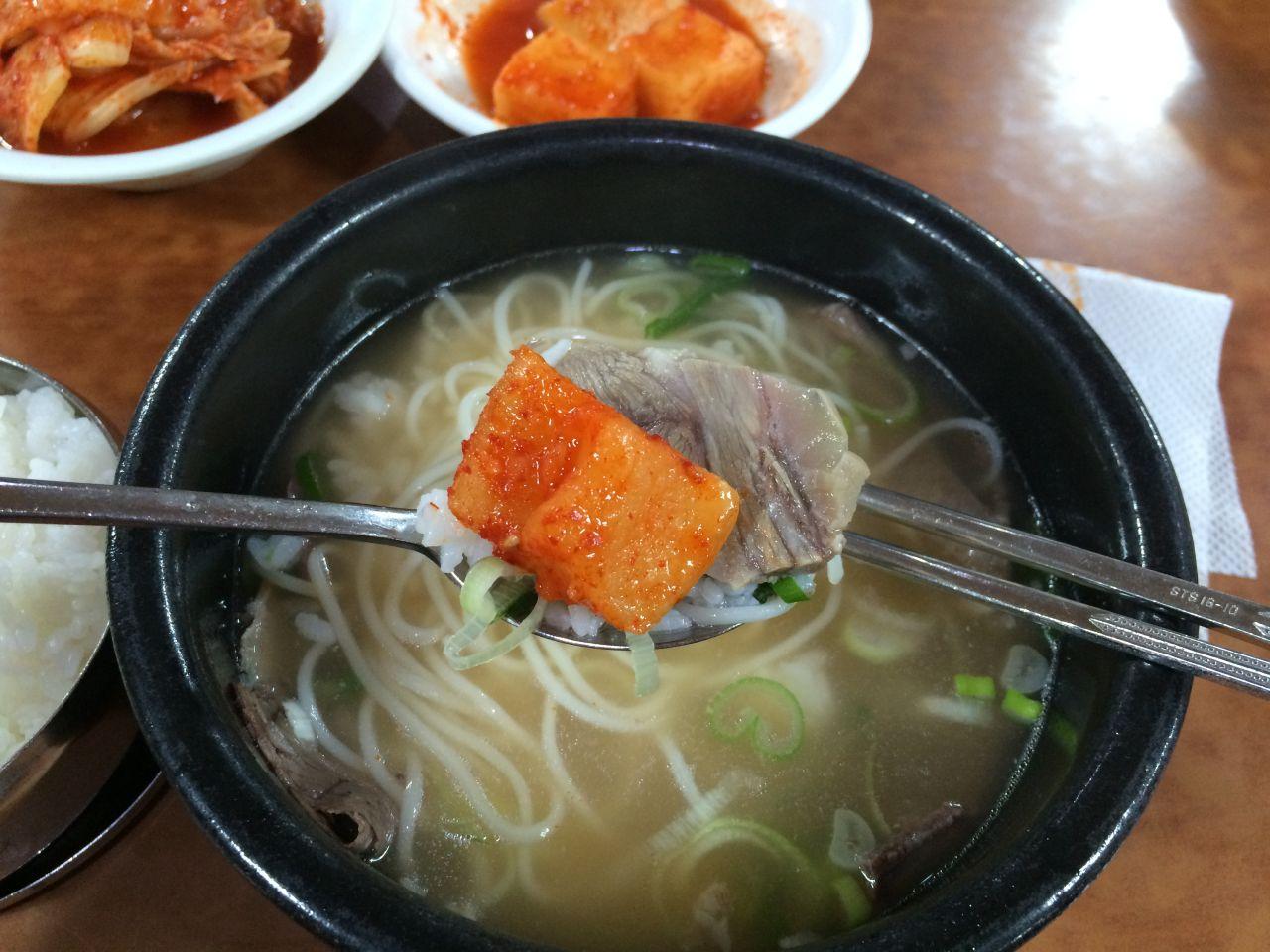 delicious bowl of traditional Korean soup with noodles, beef, and vegetables, served with tableware and ingredients.