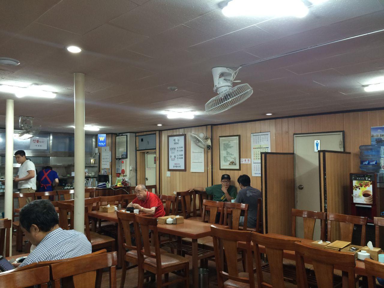 Interior view of Misungok restaurant with tables, chairs, and houseplants in a modern building; event space with T-shirt decor.