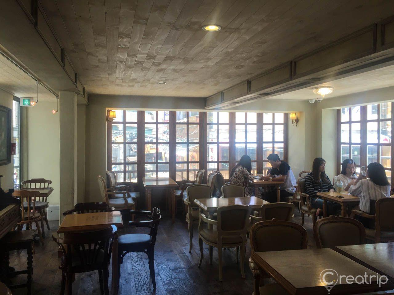 Interior of Chloris cafe with tables, chairs, and fixtures in a modern building overlooking cityscape through windows.