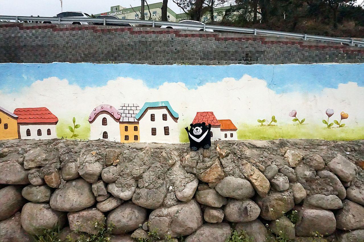 Scenic view of a house in a picturesque village by the sea in Busan, South Korea, with a beautiful sky and plants visible through a window.