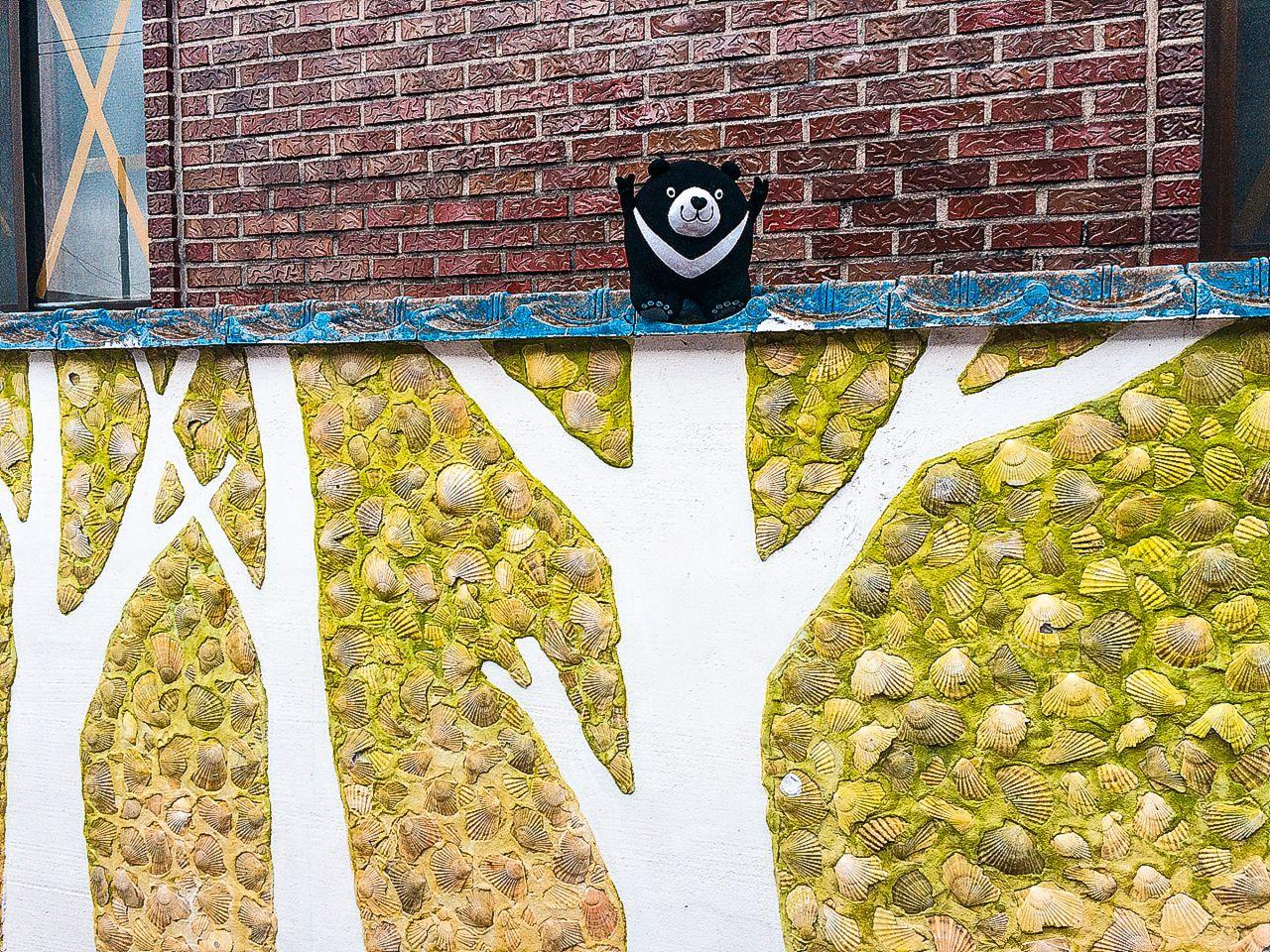 symmetrical blue wall art made of wood and twigs with plant and grass foreground in 가덕도 정거마을, Korea