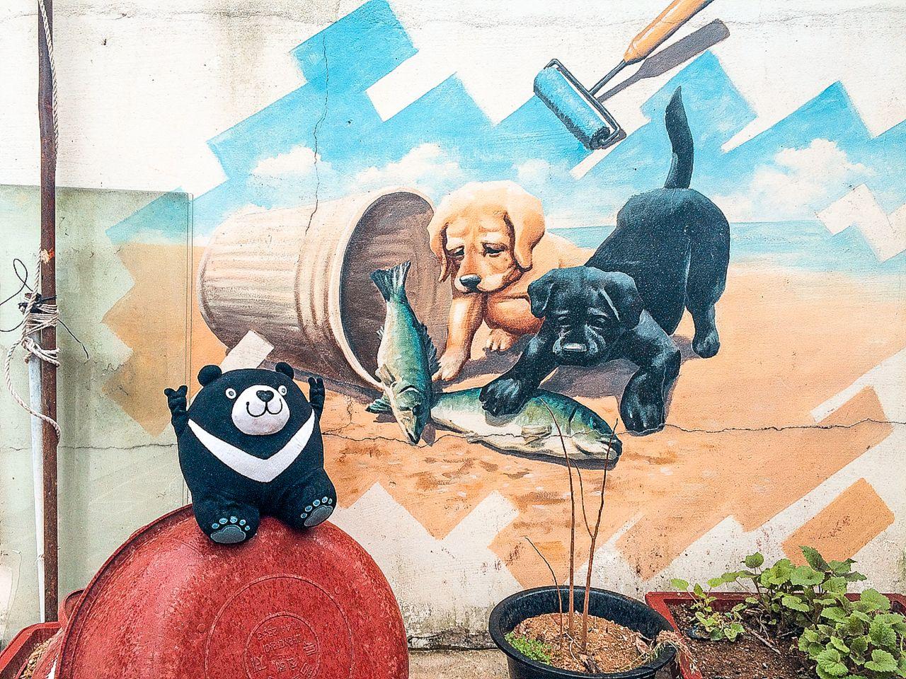 artistic painting of a blue houseplant in a flowerpot surrounded by graffiti and a working dog at 가덕도 정거마을.