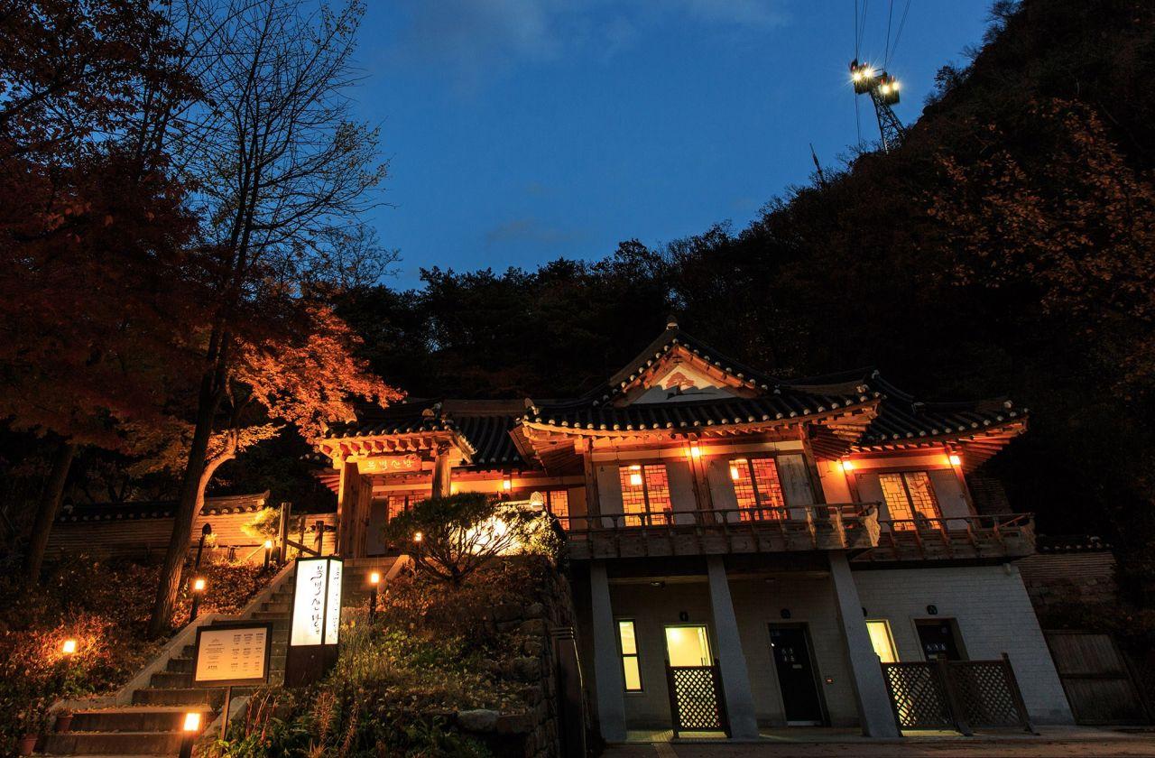 Morning view of the Biome building amidst lush nature and cloudy sky at 목멱산방, a popular restaurant along 남산 둘레길.