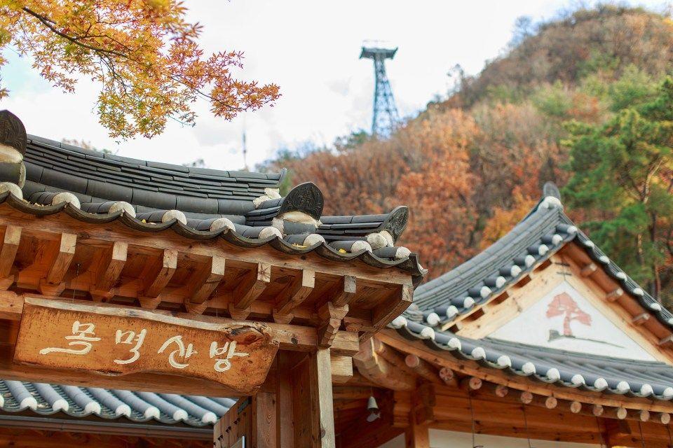 A tranquil temple surrounded by foliage and traditional Korean houses, located near Namhansanseong Fortress.