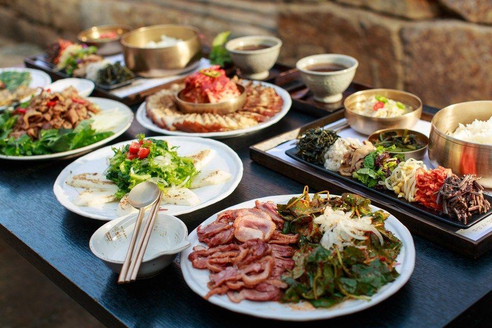 A dish of mixed leafy greens and vegetables on a white plate with tableware at 목멱산방.
