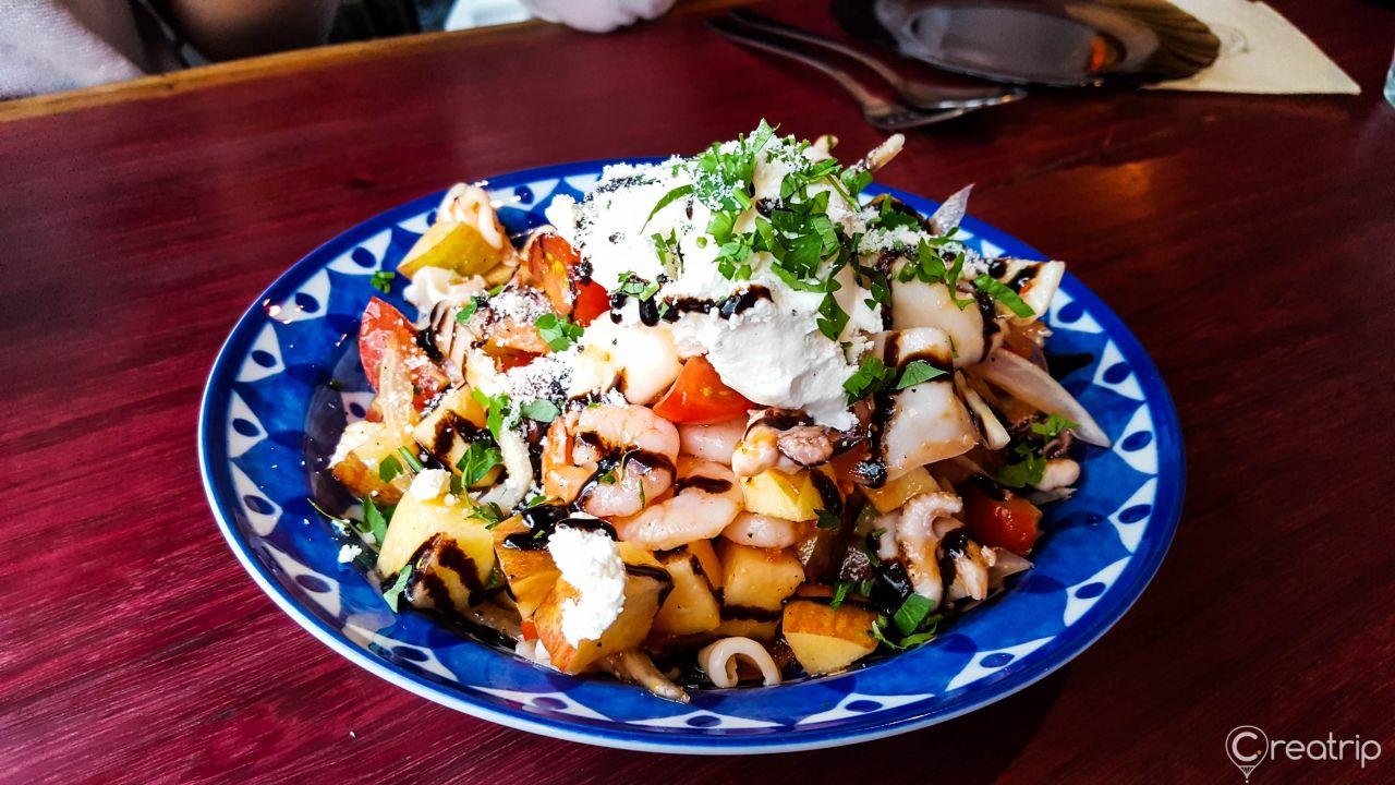 Seafood pasta dish served on a plate with salad and meat, along with tableware and ingredients on the side. Korean cuisine staple food.