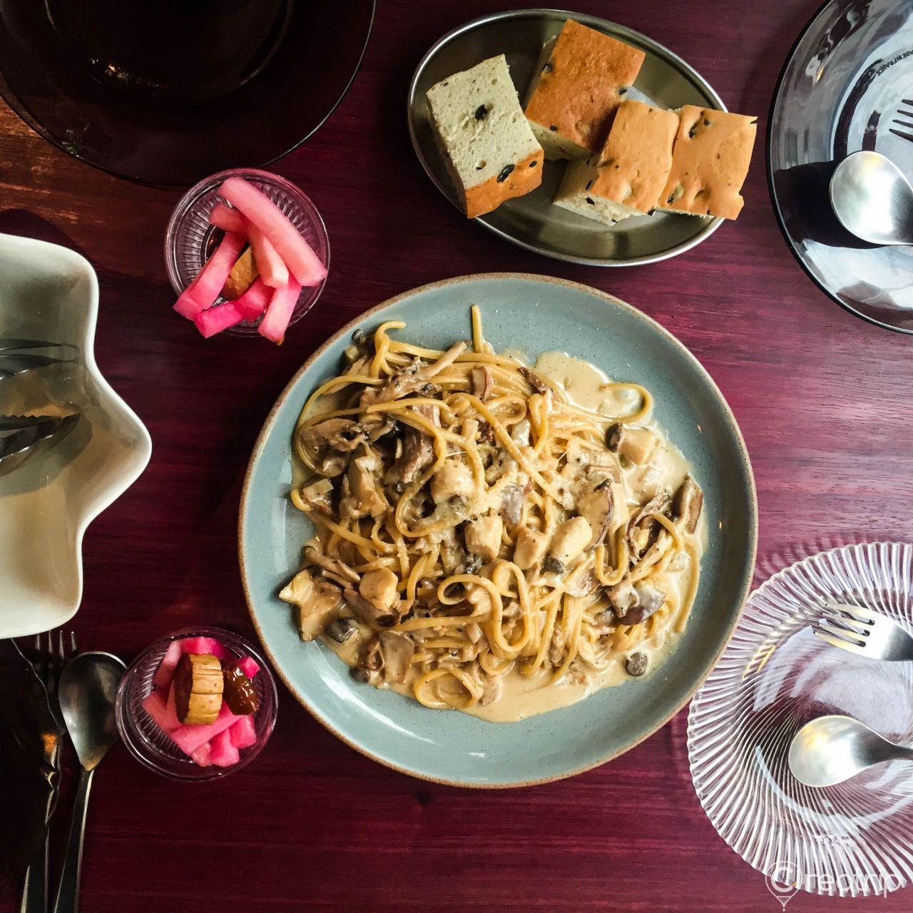 Seafood pasta dish with kitchen utensils and tableware in a Korean restaurant setting.