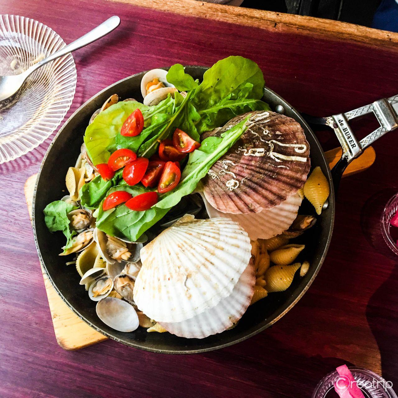 Seafood pasta dish with lemon on plate and tableware, recipe and ingredients ready for cooking.