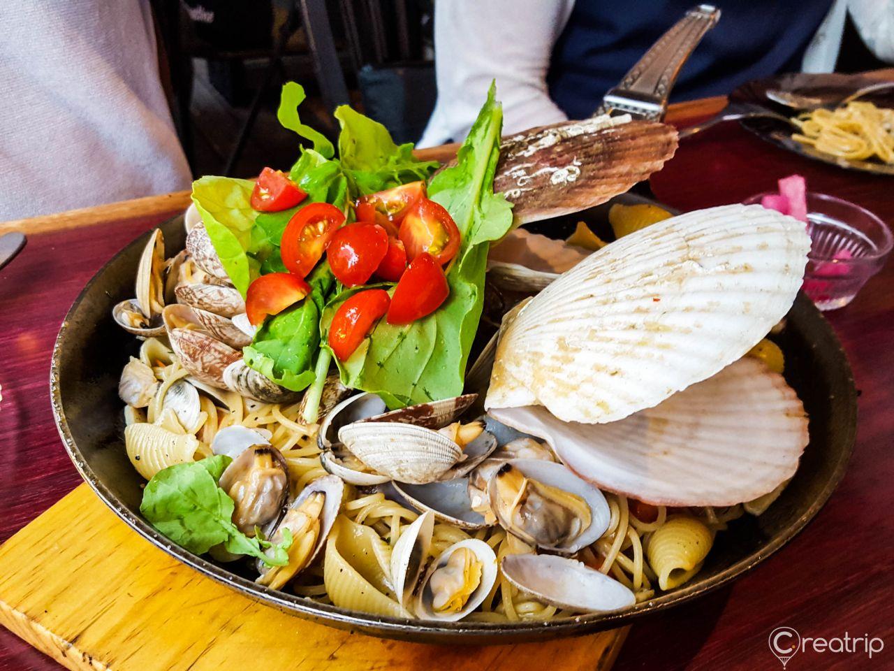 Seafood pasta dish with oysters and other fresh ingredients on tableware, inspired by Korean cuisine.