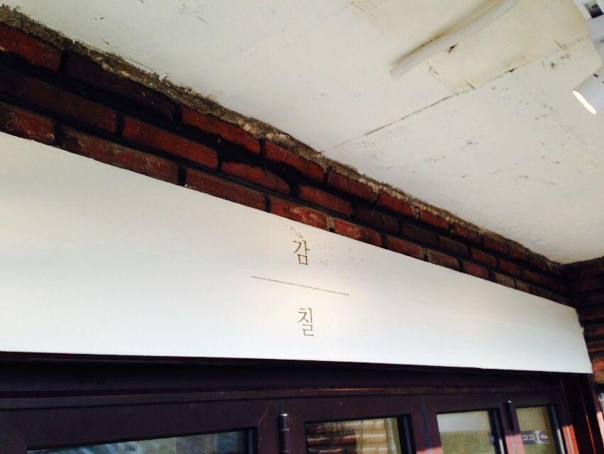 Wooden building with shaded roof and beam and font signage in Korea.